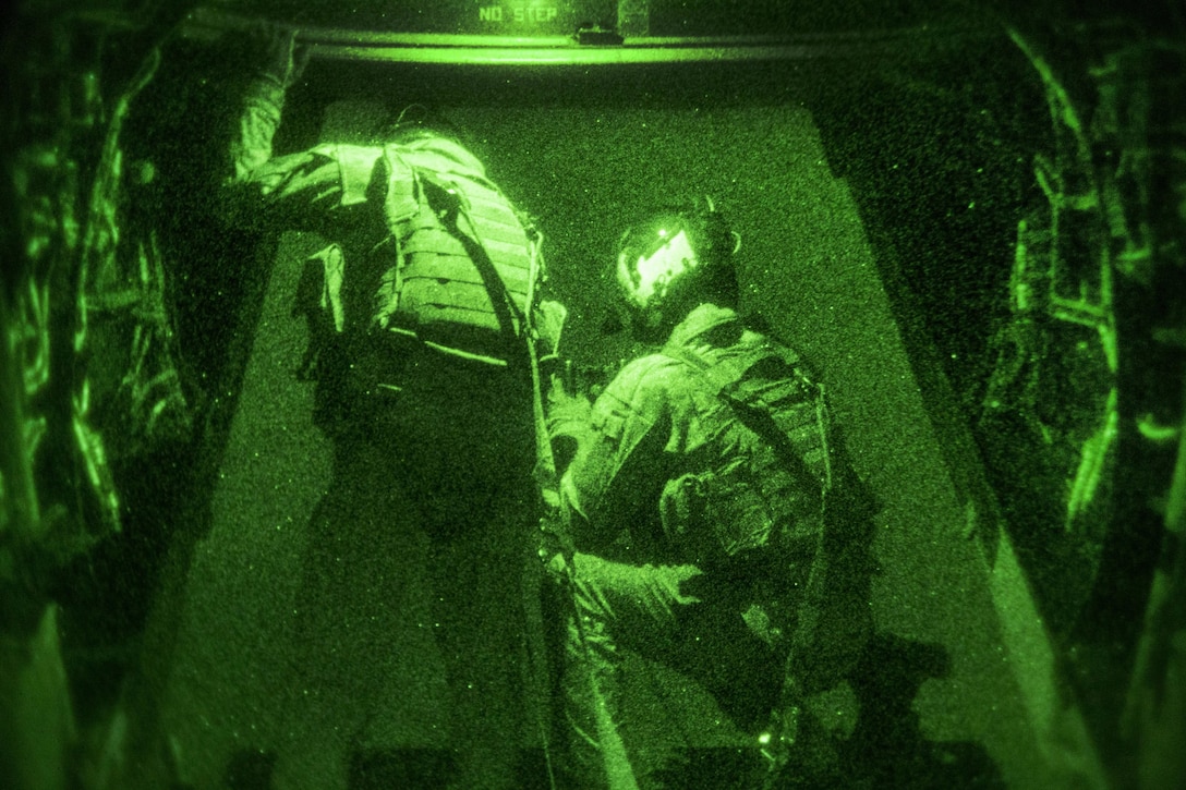 As seen through a night-vision device, U.S. Marine Corps Gunnery Sgt. Michael Kelly, left, instructs U.S. Marine Corps Lance Cpl. Kirk Goldsmith on proper air-to-ground observation techniques while conducting a tail gun live-fire exercise in Southwest Asia, Dec. 20, 2015. Kelly and Goldsmith are assigned to Marine Medium Tiltrotor Squadron 268, Special Purpose Marine Air-Ground Task Force-Crisis Response-Central Command. U.S. Marine Corps photo by Lance Cpl. Clarence Leake