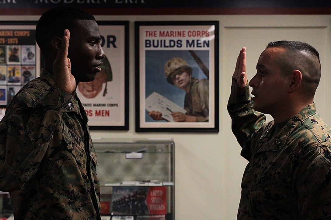 Cpl. Charles Morgan, personnel clerk at the district headquarters, repeats after CWO4 Felipe Aguilar, personnel officer at the district headquarters, during his reenlistment December 22, 2015, in the 6th Marine Corps District Museum aboard Parris Island, S.C. (Official Marine Corps photo by Cpl. John-Paul Imbody)
