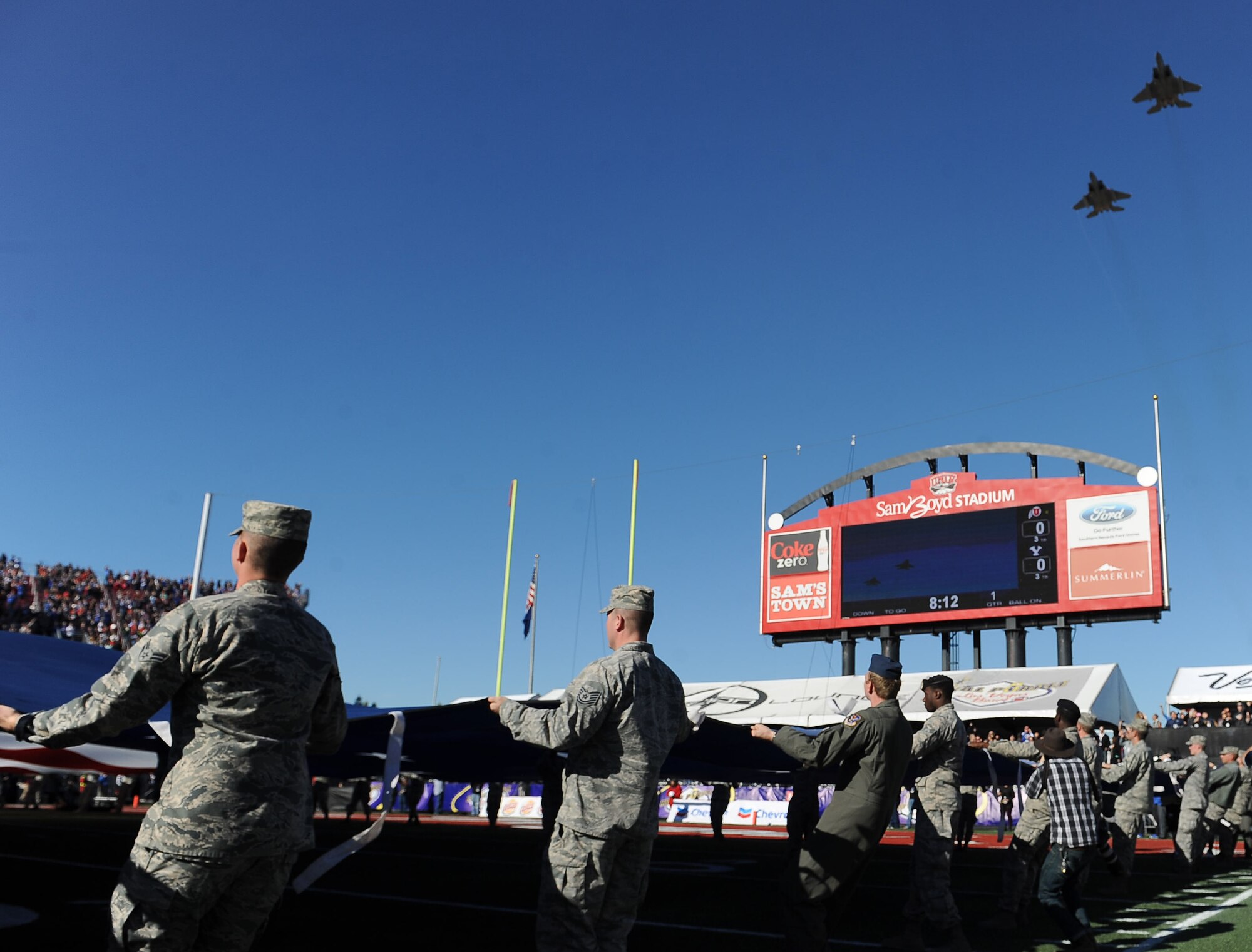 Two F-15 Eagles assigned to the 422nd Test and Evaluation Squadron preform a flyover during the national anthem at the Royal Purple Las Vegas Bowl at Sam Boyd Stadium in Las Vegas, Dec. 19, 2015. The Airmen who held the flag were afforded the opportunity to stay and watch the game between the Utah Utes and Brigham Young University Cougars. (U.S. Air Force photo by Senior Airman Thomas Spangler)