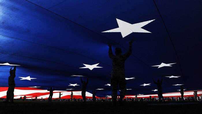 Airmen from Nellis Air Force Base, Nev., hold up the American Flag during the national anthem before the Royal Purple Las Vegas Bowl at Sam Boyd Stadium in Las Vegas, Dec. 19, 2015. Approximately 200 Airmen volunteered to hold the flag for the pre-game ceremony. (U.S. Air Force photo by Senior Airman Thomas Spangler)