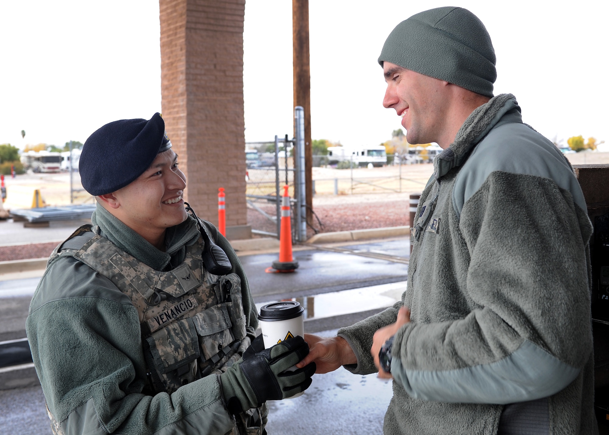 U.S. Air Force Chaplain (Capt.) Justin Szeker, 355th Fighter Wing chaplain, hands Airman Ricardo Venancio, 355th Security Forces Squadron, a cup of hot chocolate at Davis-Monthan Air Force Base, Ariz., Dec. 14, 2015. Szeker and Staff Sgt. George Mena, 355th Fighter Wing chaplain’s assistant, went around to the entry control points to give hot chocolate to all the SFS Airmen who were out in the cold. (U.S. Air Force photo by Senior Airman Cheyenne A. Powers/ Released)

