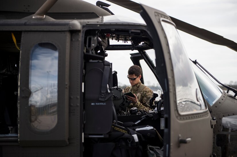 A pilot assigned to the 3rd Combat Aviation Brigade runs through a pre-flight checklist on a UH-60 Black Hawk, Dec. 28, 2015, before taking off at Joint Base Charleston, S.C. Weapons Station. More than 20 helicopters returned to the U.S. from various United States European Command bases via cargo ship. The 841st Transportation Battalion from Joint Base Charleston unloaded the helicopters and the 3rd CAB flew the aircraft back to their home  station, Hunter Army Airfield, Ga. (U.S. Air Force photo/Senior Airman Jared Trimarchi) 