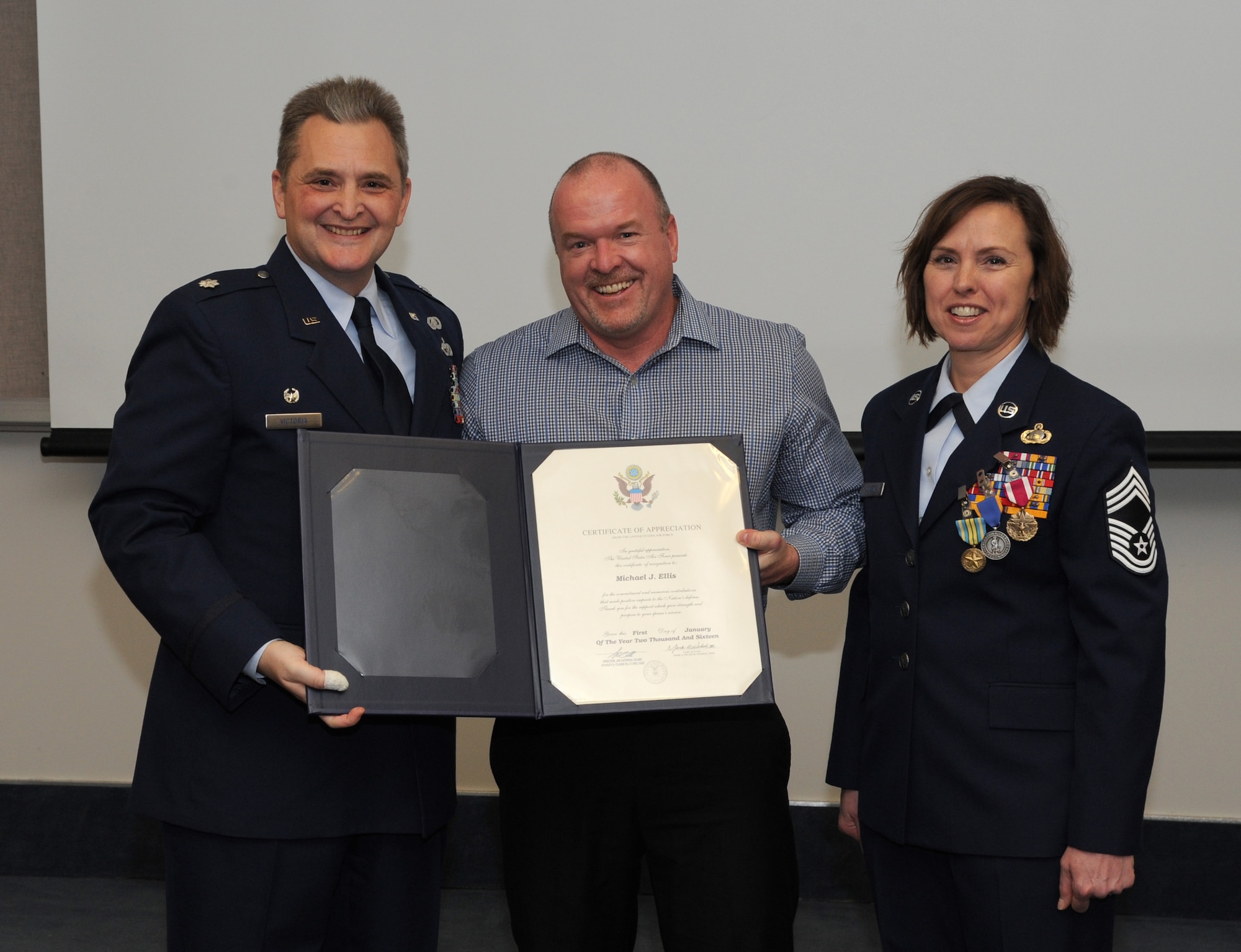 Oregon Air National Guard Lt. Col. Anthony Victoria, 142nd Fighter Wing Force Support Squadron commander, left, presents a Certificate of Appreciation from the United States Air Force to Michael Ellis, center, during a formal retirement ceremony from the Air National Guard for Chief Master Sgt. Jean Allen, right, Dec. 22, 2015, Portland Air National Guard Base, Ore. (Air National Guard photo by Tech. Sgt. John Hughel, 142nd Fighter Wing Public Affairs)