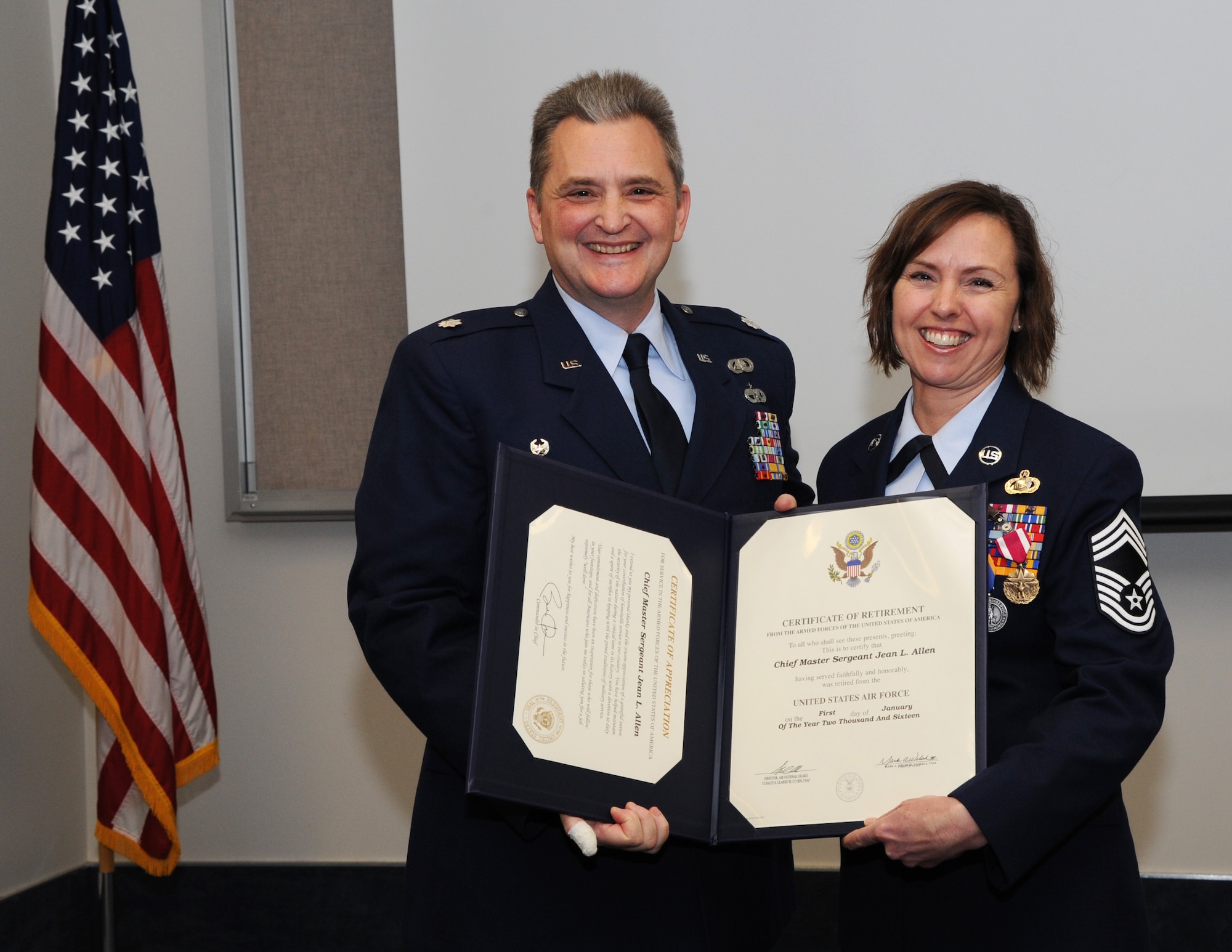 Oregon Air National Guard Lt. Col. Anthony Victoria, 142nd Fighter Wing Force Support Squadron commander, left, presents The Certificate of Retirement from the United States Air Force to Chief Master Sgt. Jean Allen, right, during her formal retirement ceremony from the Air National Guard, Dec. 22, 2015, Portland Air National Guard Base, Ore. (Air National Guard photo by Tech. Sgt. John Hughel, 142nd Fighter Wing Public Affairs)