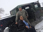 Sgt. 1st Class Christopher Vaillancourt, Headquarters and Headquarters Company, 717th Brigade Support Battalion, takes a chilly photo with a Roswell citizen he helped transport to the Fresenius Medical Care center Dec. 29. One of the missions currently being performed by members of the New Mexico National Guard is the transportation of Roswell, N.M., citizens in need of dialysis treatments. Citizens were snowed in to their homes due to a winter blizzard that caused roads to be impassable. For at least two days, local members of the National Guard traversed the icy, snow packed conditions to help citizens in need. (Courtesy photo)