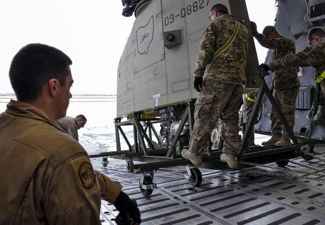 U.S. soldiers and airmen unload a helicopter from a C-5M Super Galaxy on Bagram Airfield, Afghanistan, Dec. 26, 2015. The soldiers are assigned to Task Force Destiny, and the airmen are assigned to the 9th Airlift Squadron, deployed from Dover Air Force Base, Delaware. The C-5 Galaxy is a heavy airlifter with intercontinental range and is the largest U.S. military aircraft capable of carrying more than 270,000 pounds of cargo. U.S. Air Force photo by Tech. Sgt. Nicholas Rau