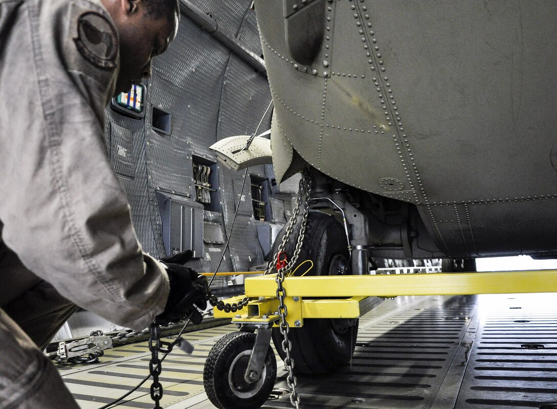 U.S. Air Force Senior Airman Julian Brown detaches chains while unloading a helicopter from a C-5M Super Galaxy on Bagram Airfield, Afghanistan, Dec. 26, 2015. Brown is assigned to the 9th Airlift Squadron, deployed from Dover Air Force Base, Delaware. U.S. Air Force photo by Tech. Sgt. Nicholas Rau