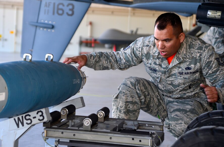 Tech. Sgt. David Yocom, 432nd Aircaft Maintenance Squadron weapons load crew chief, guides in a bomb lift during the Load Crew of the Quarter competition Oct. 23, 2015, at Creech Air Force Base, Nevada. The LCOQ competition is a friendly competition to increase readiness while also increasing morale at the same time. (U.S. Air Force photo by Airman 1st Class Christian Clausen/Released)