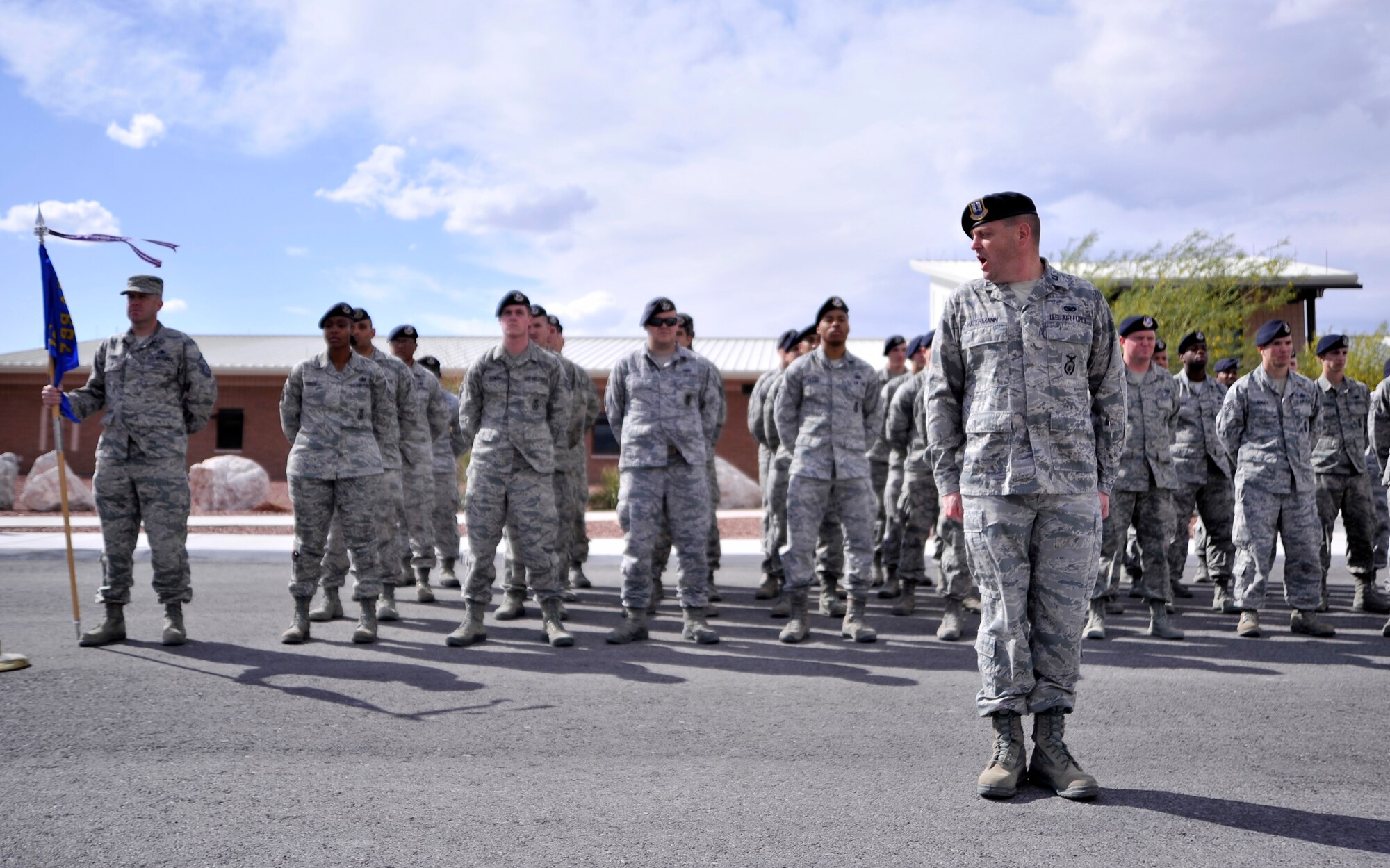 Capt. Chad Hafermann, 799th Security Forces Squadron operations officer, calls the formation to attention during a retreat ceremony May 15, 2015, at Creech Air Force Base, Nevada. During National Police Week, security forces Airmen and local law enforcement personnel around the Air Force take part in various ceremonies to show their support for fallen law enforcement officials from across the nation. (U.S. Air Force photo by Airman 1st Class Christian Clausen/Released)