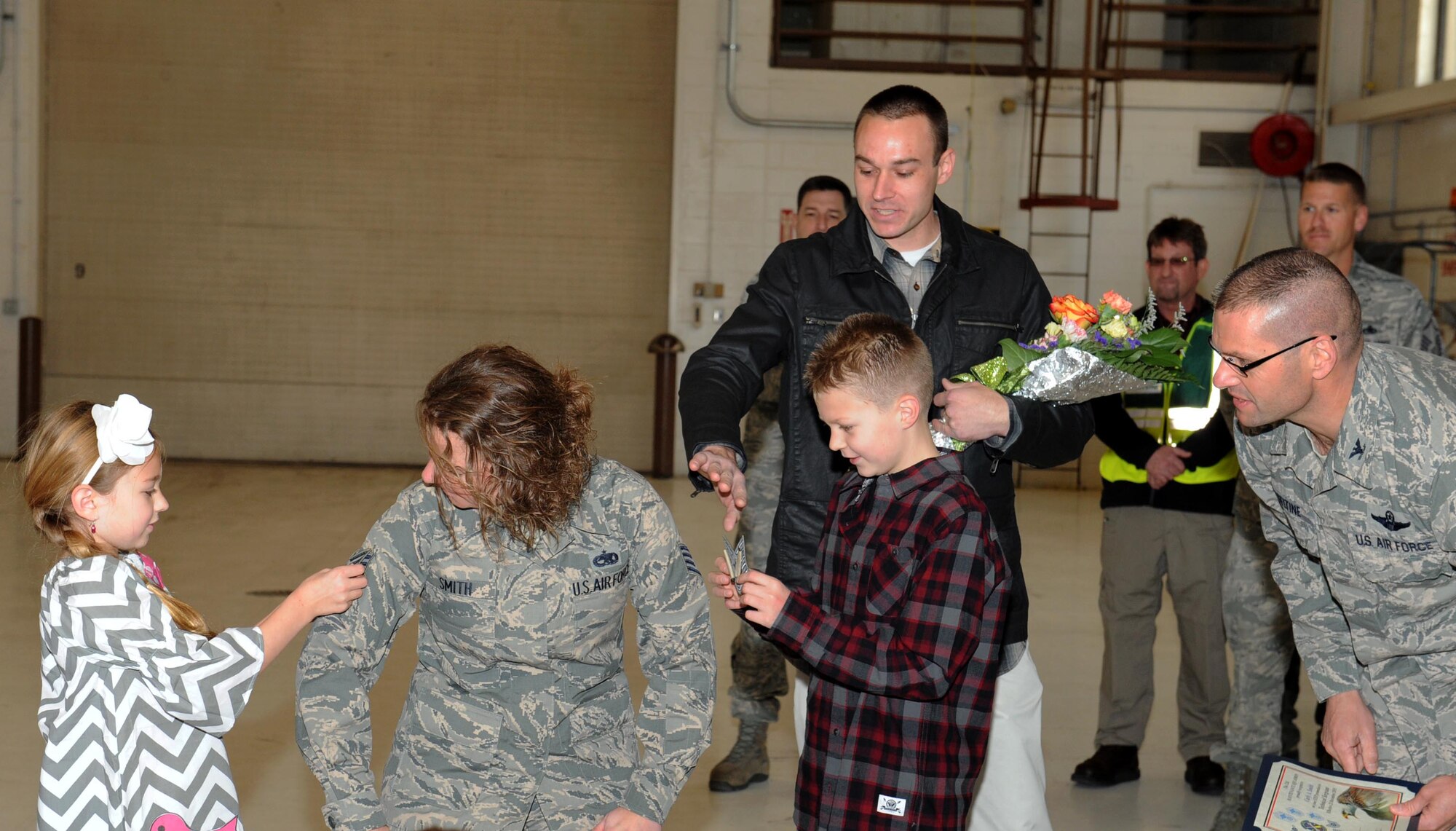 Tech. Sgt. Carly Smith, 22nd Maintenance Squadron munitions operations NCO in charge, watches as her children tack on technical sergeant stripes, Dec. 23, 2015, at McConnell Air Force Base, Kan. Smith was promoted from the rank of staff sergeant to technical sergeant through the Stripes for Exceptional Performance program, which commanders use to promote deserving Airmen one rank without testing. (U.S. Air Force photo/Senior Airman David Bernal Del Agua)