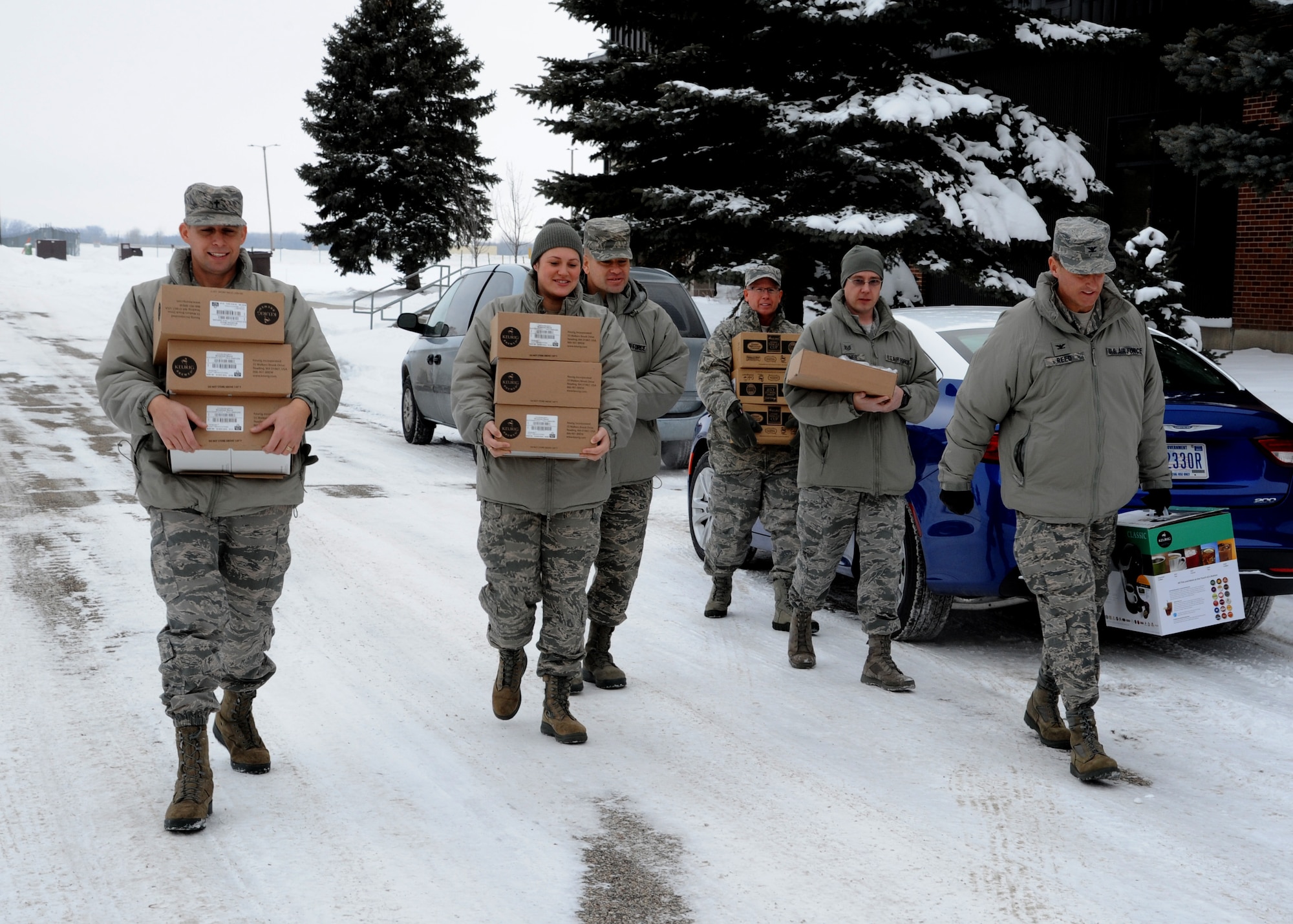 Members of the 319th Air Base Wing chapel team and wing leadership carry coffee supplies Dec. 30, 2015, on Grand Forks Air Force Base, North Dakota. The chapel team delivered eight Keurig coffee makers and 10 pallets of Keurig K-cups to different units. The coffee and machines were donated to Grand Forks AFB. (U.S. Air Force photo by Airman 1st Class Ryan Sparks/Released)