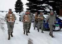 Members of the 319th Air Base Wing chapel team and wing leadership carry coffee supplies Dec. 30, 2015, on Grand Forks Air Force Base, North Dakota. The chapel team delivered eight Keurig coffee makers and 10 pallets of Keurig K-cups to different units. The coffee and machines were donated to Grand Forks AFB. (U.S. Air Force photo by Airman 1st Class Ryan Sparks/Released)