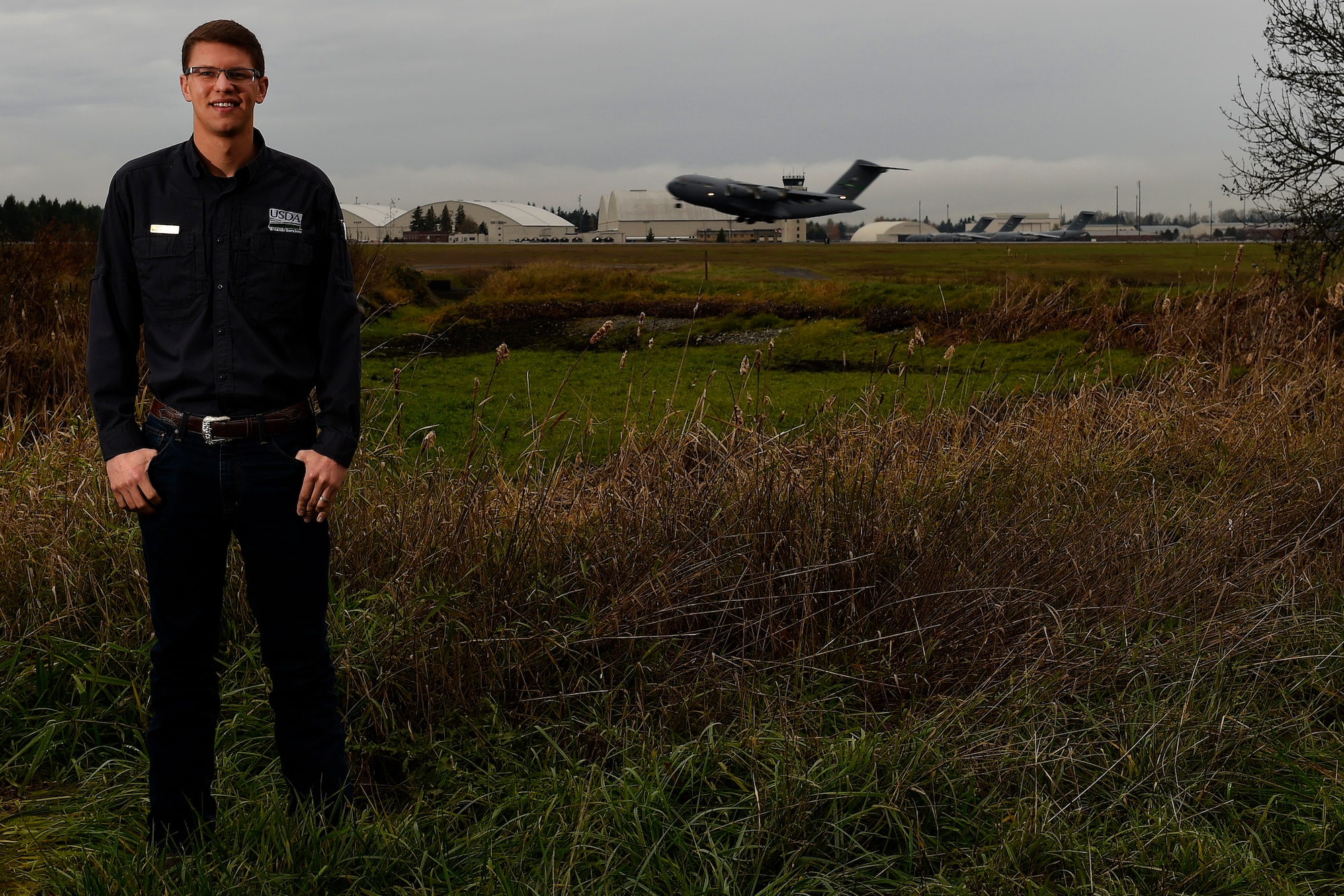 Mr. Christopher Lang, McChord Field Wildlife Biologist with the U.S. Department of Agriculture Wildlife Services, poses for a photo near the McChord Field flight line, Dec. 3, 2015 at Joint Base Lewis-McChord, Wash. Lang manages the Bird Aircraft Strike Hazard and Wildlife Hazard Working Groups within his primary area of responsibility at McChord Field and with the 62nd Airlift Wing. (U.S. Air Force photo/Tech. Sgt. Tim Chacon)