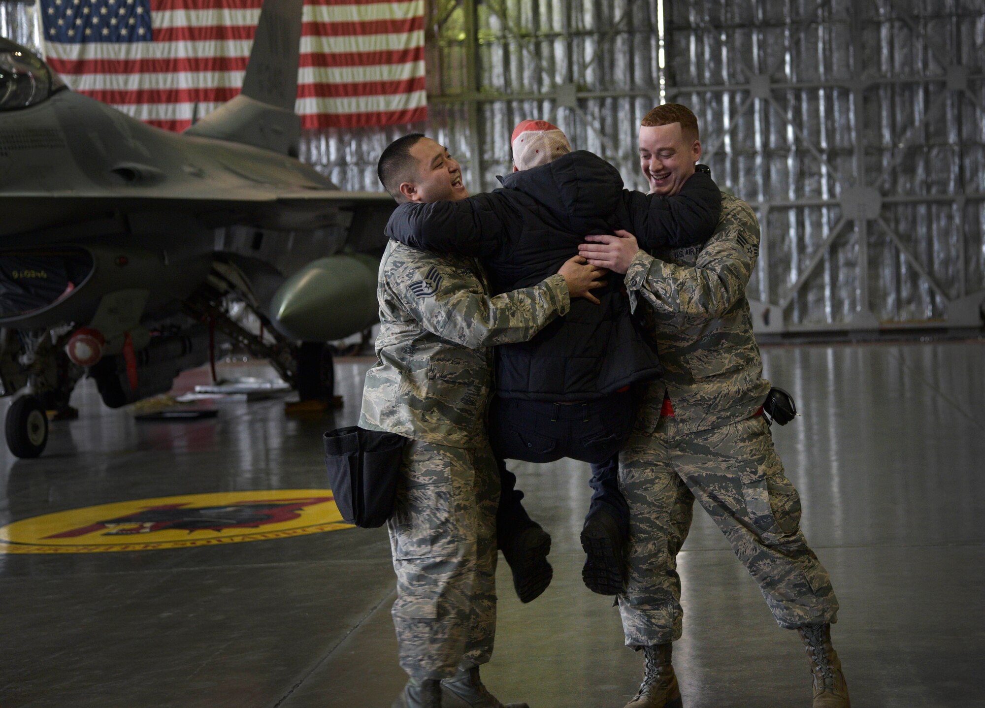 An observer congratulates U.S. Air Force Staff Sgt. Nathan Hadama, 35th Aircraft Maintenance Squadron weapons, 13th Aircraft Maintenance Unit team chief, and Senior Airman Donald Ramsey, 35 AMXS, 13 AMU weapons load crew member, after a quarterly weapons loading competition at Misawa Air Base, Japan, Dec. 30, 2015. During the competition, two teams of three Airmen were challenged to quickly install upwards of three types of armaments to a stationary F-16 Fighting Falcon in the quickest time possible. (U.S. Air Force photo by Senior Airman Deana Heitzman/Released)    