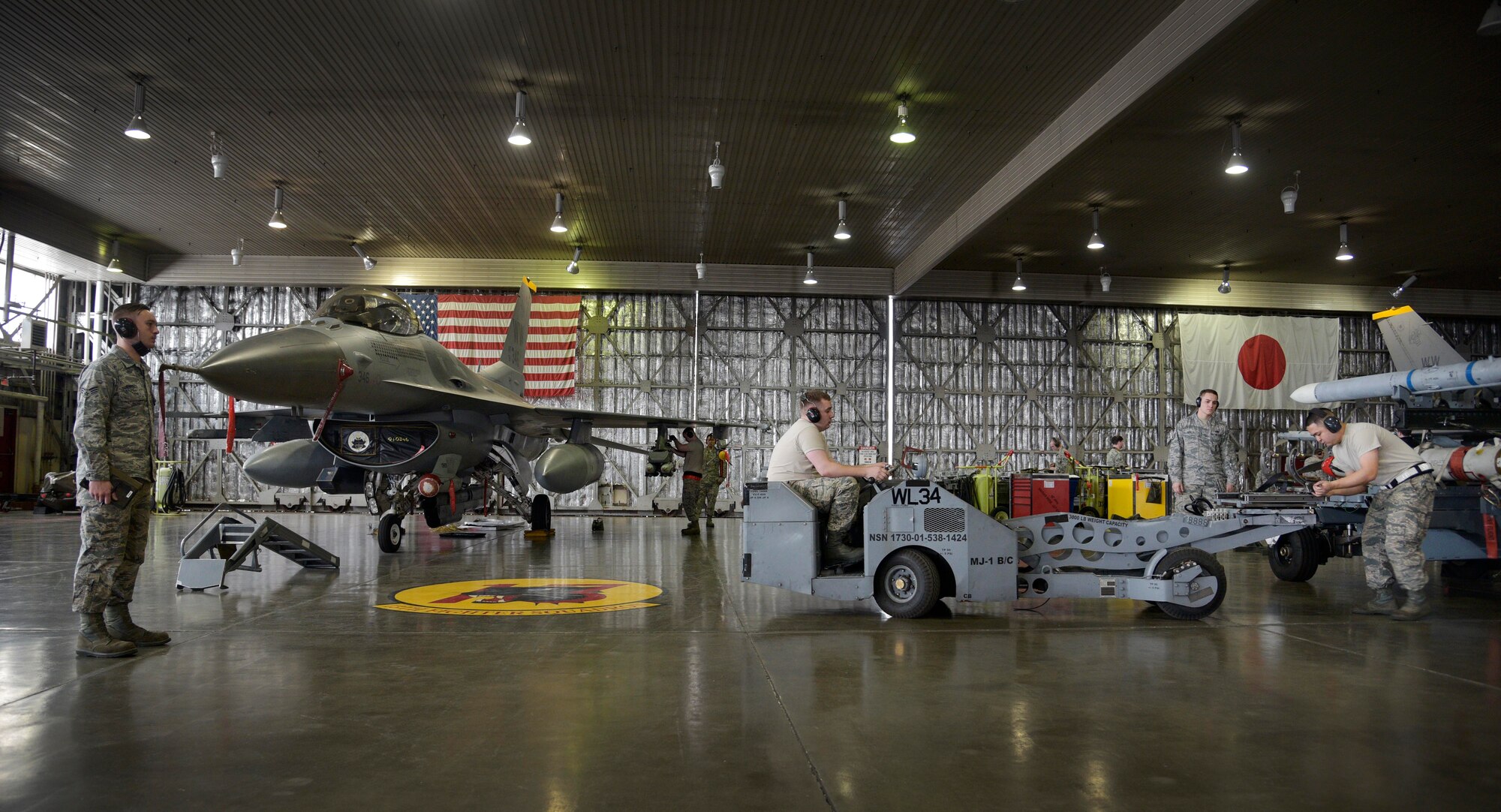 A weapons load team from the 35th Aircraft Maintenance Squadron prepares to load a weapons system while being inspected by a standardization load crew from the 35th Maintenance Group during a quarterly weapons loading competition at Misawa Air Base, Japan, Dec. 30 2015. The objective of the weapons load crew competition was to gauge how quickly and efficiently teams of Airmen are able to arm an F-16 Fighting Falcon. (U.S. Air Force photo by Senior Airman Deana Heitzman/Released) 