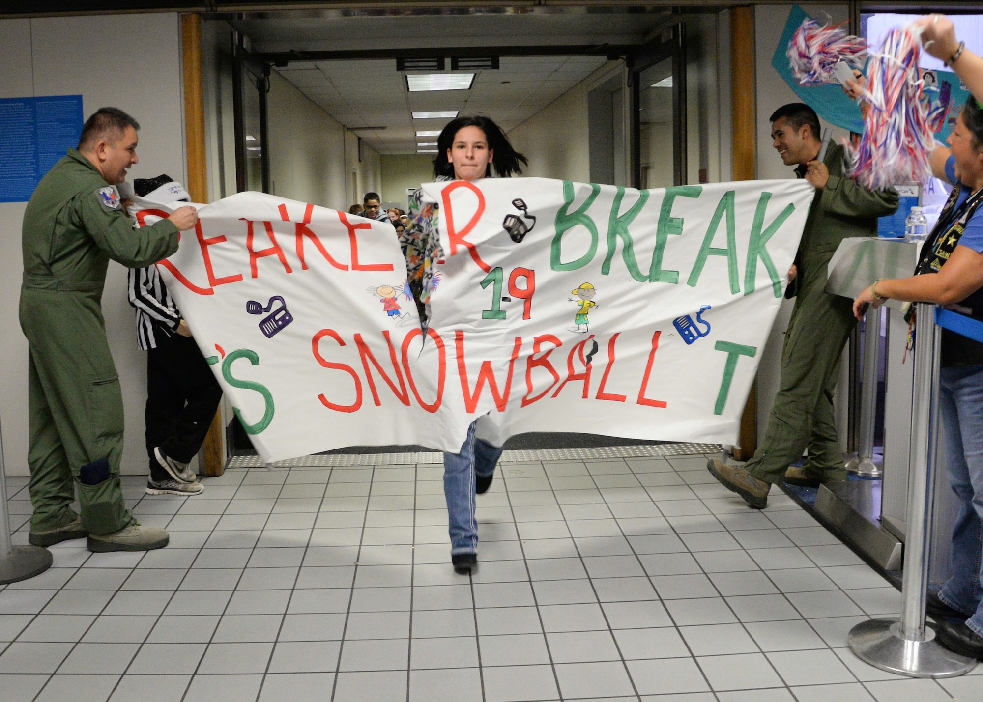 U.S. Air Force Senior Master Sgt. Robert Merrill and Tech. Sgt. Gabriel Garcia Diaz, both flight engineers assigned to the 136th Operations Group, Texas Air National Guard from Naval Air Station Fort Worth Joint Reserve Base, Texas, hold a paper banner for arriving Snowball Express attendees at Dallas-Fort Worth Airport, Dec. 12, 2015. Snowball Express is an organization dedicated to the children of military members who have died while on active duty since Sept. 11. (Air National Guard photo by Tech. Sgt. Vanessa Reed/released)