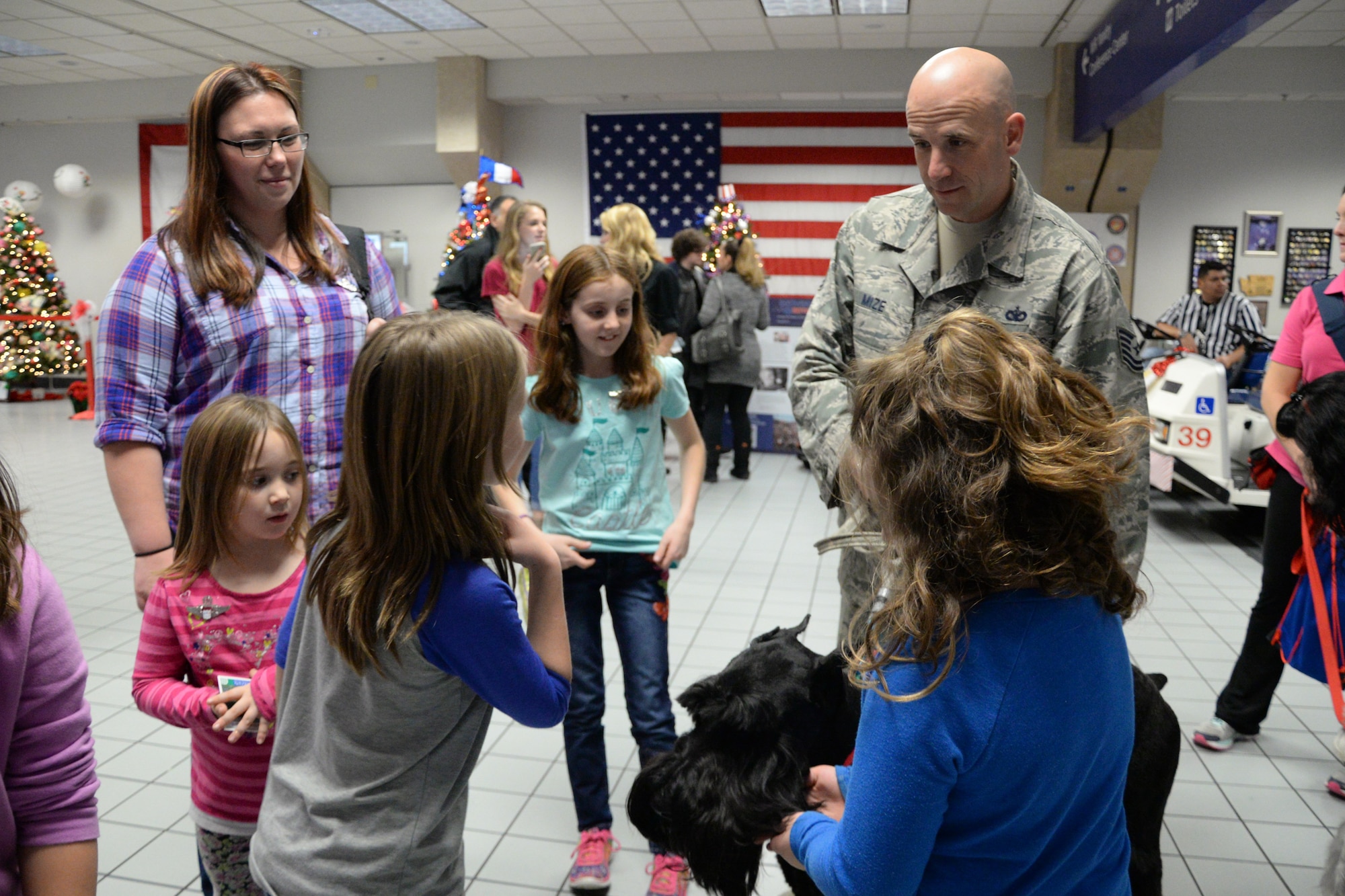 U.S. Air Force Tech. Sgt. Mark Mize, a squad leader from the 136th Security Forces Squadron, Texas Air National Guard from Naval Air Station Fort Worth Joint Reserve Base, Texas, and his therapy dog, Sully, welcome families arriving for Snowball Express 2015 at Dallas-Fort Worth Airport, Dec. 12, 2015. Snowball Express is an organization dedicated to the children of military members who have died while on active duty since Sept. 11. (Air National Guard photo by Tech. Sgt. Vanessa Reed/released)