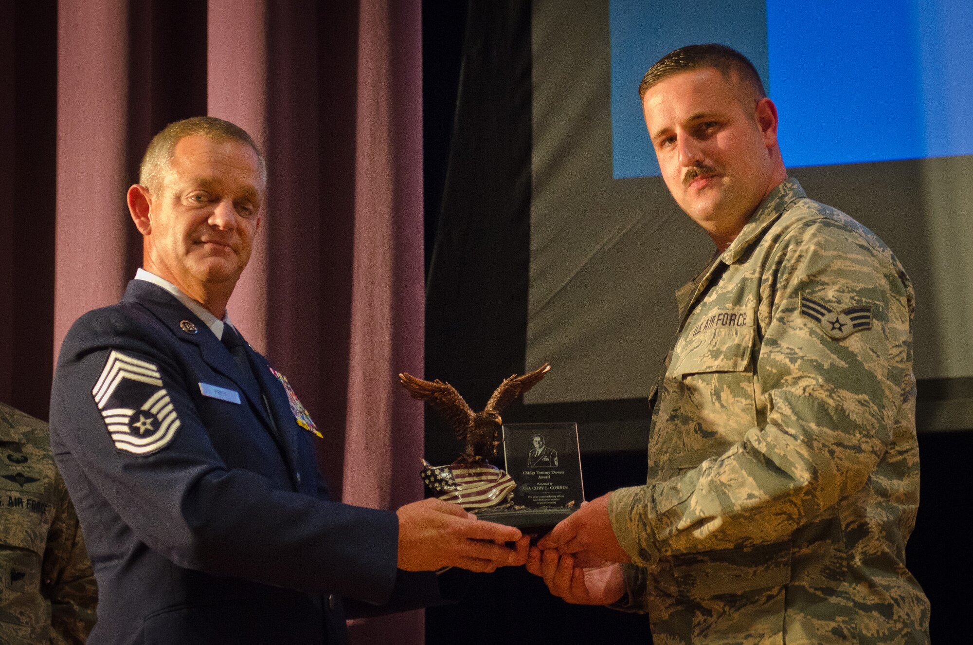 Chief Master Sgt. Brian Pritt (left), air transportation manager for the 130th Logistics Readiness Squadron, presents the Chief Master Sgt. Tommy Downs award to Senior Airman Cory Corbin, an air transportation journeyman in the Kentucky Air National Guard’s 123rd Logistics Readiness Squadron, during a ceremony at the Kentucky Air Guard Base in Louisville, Ky., Oct. 13. 2015. The award, named for a former Kentucky Air Guard command chief, is given annually to the top air transportation journeyman in the Air National Guard for excellence in aerial port operations. (U.S Air National Guard photo by Senior Airman Joshua Horton)