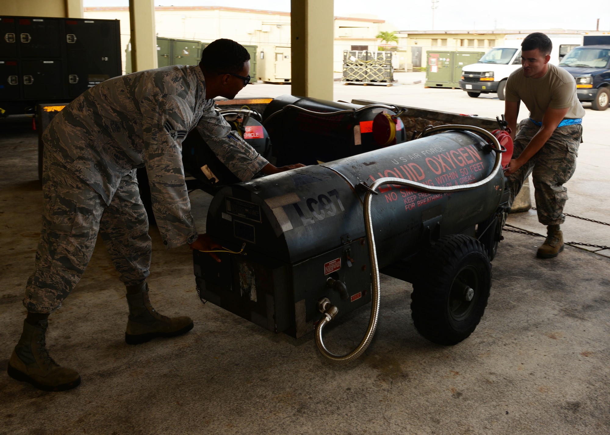 Senior Airmen Ferral Ceaser (left) and Kevin Hakala, 36th Maintenance Squadron electrical and environmental technicians, push a liquid oxygen cart for transportation, Dec. 1, 2015, at Andersen Air Force Base, Guam. After inspecting the cart, the team takes the cart to cryogenics to be filled with liquid oxygen. (U.S. Air Force photo/Senior Airman Cierra Presentado)