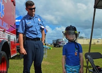 SANTA RITA, Guam (Dec. 19, 2015) Captain Douglas Kelly from the Navy Fire and Emergency Services on Naval Base Guam helps a child dawn a firefighting helmet during the first ever Team 15 Day event December 19.  Team 15 Day, hosted by Submarine Squadron 15, is an event that brings together Sailors and families from the submarine community on Guam to educate them on Navy support services and acclimate new arrivals to life on Guam.