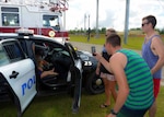 SANTA RITA, Guam (Dec. 19, 2015) Sailors and family members assigned to the Los Angeles class fast-attack submarine USS Key West (SSN 722), take photos of their children exploring a Guam Police Department vehicle during the first ever Team 15 Day event December 19.  Team 15 Day, hosted by Submarine Squadron 15, is an event that brings together Sailors and families from the submarine community on Guam to educate them on Navy support services and acclimate new arrivals to life on Guam.