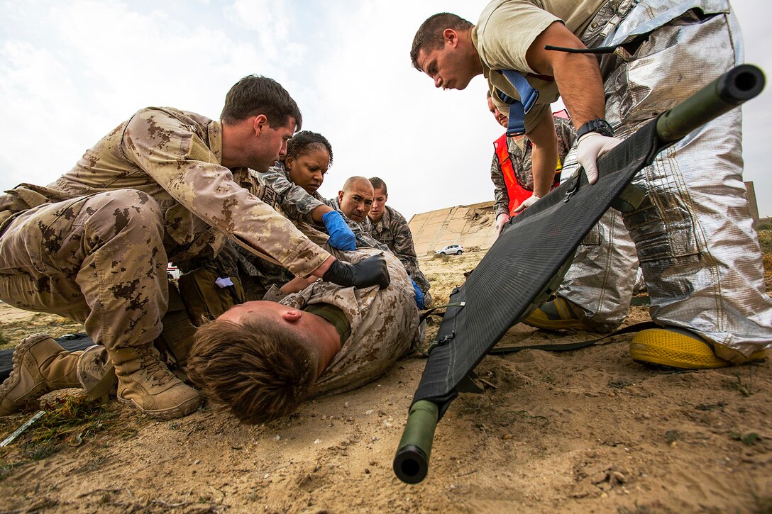 U.S. Navy and Air Force medical personnel load a simulated casualty onto a stretcher during a mass casualty exercise at an undisclosed location in Southwest Asia, Dec. 23, 2015. U.S. and Canadian troops participated in the joint exercise to hone the coalition’s medical response capabilities. U.S. Marine Corps photo by Sgt. Rick Hurtado