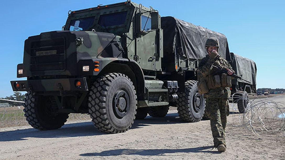 Lance Cpl. Tyler Brinkman, an entry control point guard and radio operator with Headquarters Battalion, Communications Company, 2nd Marine Division, relays information through a radio as a 7-ton truck carrying Marines travels though the command post exercise ECP at Landing Zone Bluebird on Marine Corps Base Camp Lejeune, N.C., Jan. 28, 2015.  ECP guard’s duty is to control movement going in and out of the compound and maintain awareness at all times to keep the compound safe.  (U.S. Marine Corps photo taken by Lance Cpl. Alexander Mitchell/released)