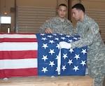 New York Army National Guard Staff Sgt. Luis Pagan, an instructor at the week-long Honor Guard Academy held at Camp Smith Training Site near Peekskill, New York, the week of Jan. 26-30, watches as Pfc. Miguel Paulino adjusts the American flag covering a casket during training on Jan. 29, 2015. The instructors watched every move the 15 students made during the academy and correct errors on the spot. 