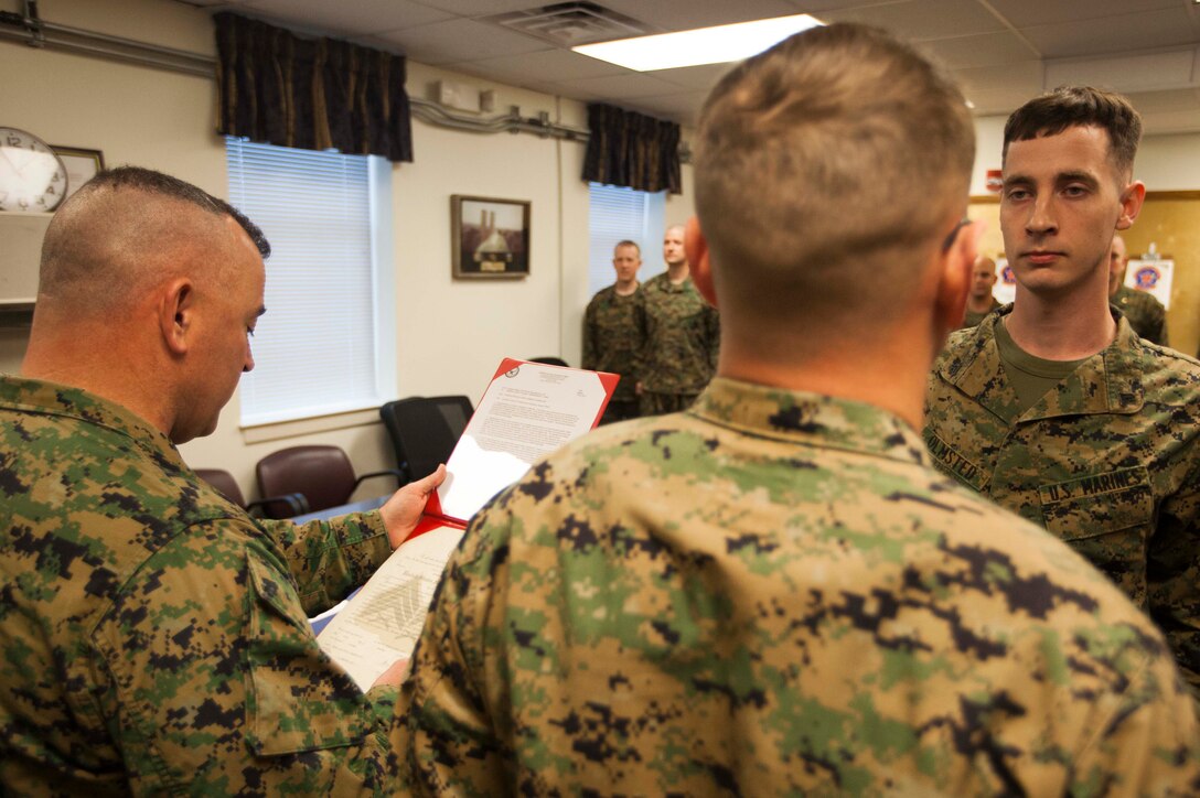 U.S. Marine Corps Master Gunnery Sgt. Glenn Cooper, left, 22nd Marine Expeditionary Unit (MEU) operations chief and native of Virginia Beach, Va., reads the promotion warrant for Sgt. Todd Olmsted, right, MEU Marine air-ground task force planner and native of Brandon, Miss., during a promotion ceremony at Marine Corps Base Camp Lejeune, N.C., Feb. 2, 2015. (U.S. Marine Corps photo by Sgt. Austin Hazard/Released)