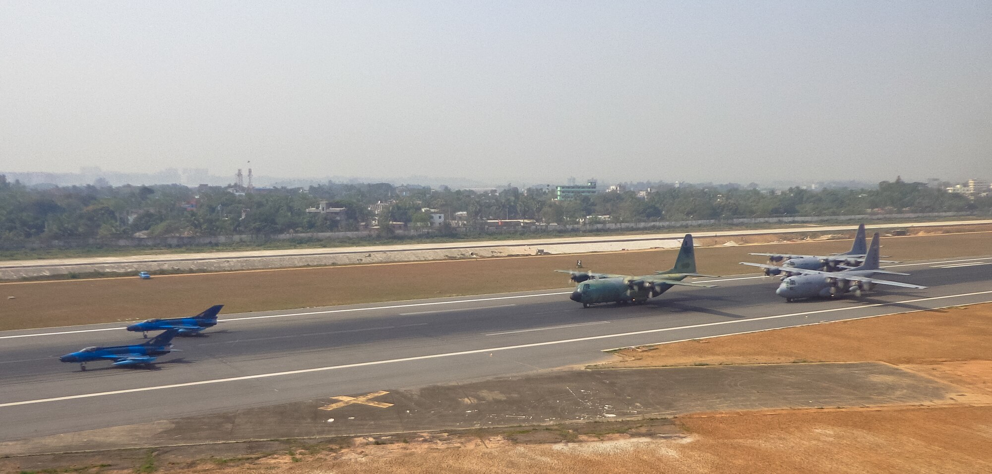 Two Bangladesh F-7BG Defenders, a BAF C-130B Hercules, and two U.S. Air Force C-130H Hercules aircraft prepare to take off from BAF Base Bangabandhu,  Bangladesh, during Exercise COPE SOUTH Jan. 28, 2015. The U.S. C-130H is assigned to the 374th Airlift Wing, Yokota Air base, Japan; the BAF F-7BGs are assigned to 5th Squadron and the BAF C-130B is assigned to 101st Special Flying Unit at BAF Base Bangabandhu. COPE SOUTH is a Pacific Air Forces-sponsored, bilateral tactical airlift exercise conducted in Bangladesh, with a focus on cooperative flight operations, day and night low-level navigation, tactical airdrop, and air-land missions as well as subject-matter expert exchanges in the fields of operations, maintenance and rigging disciplines. (Courtesy photo by Bangladesh Air Force)