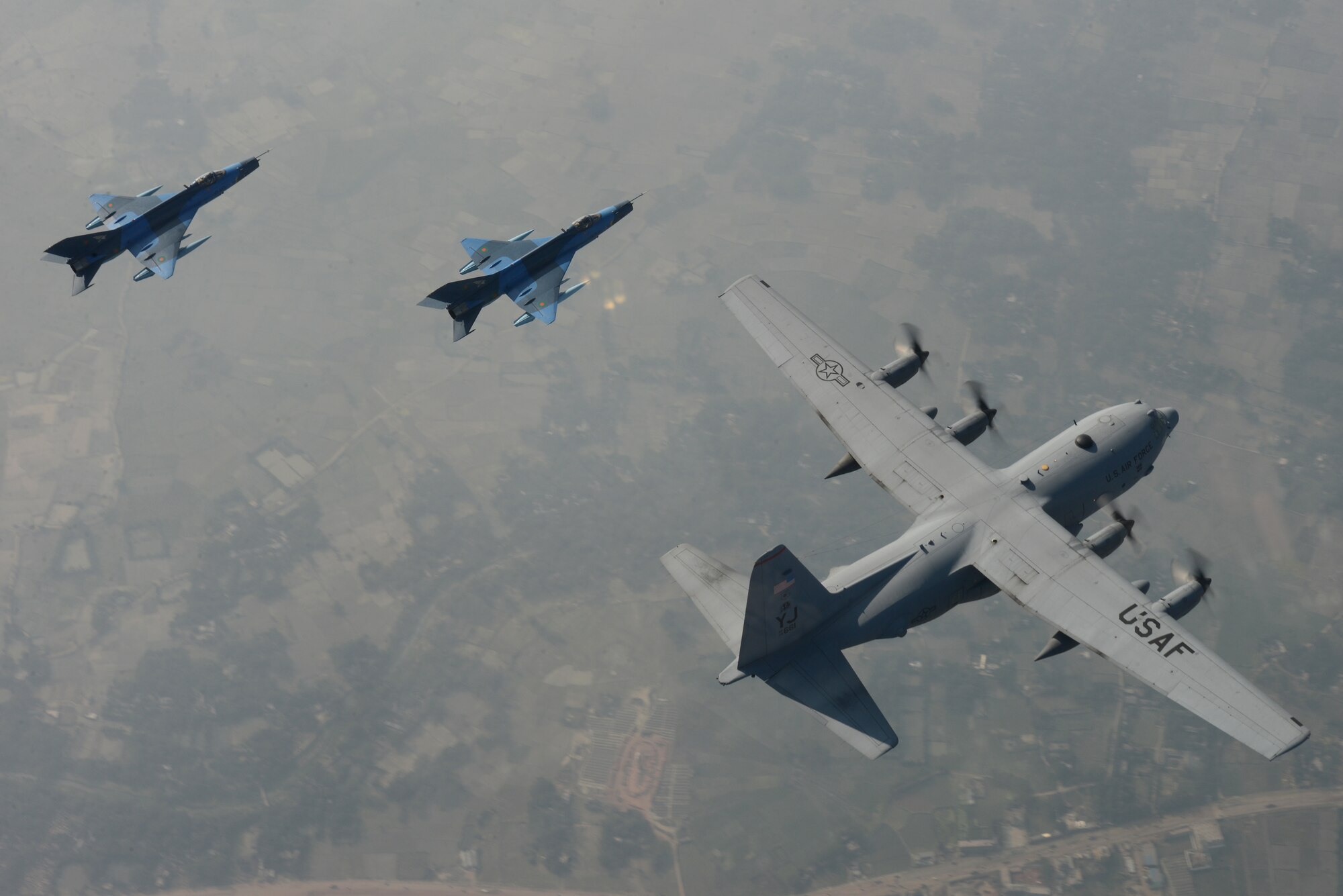 Two Bangladesh Air Force F-7BG Defenders from 5th Squadron, BAF Base Bangabandhu, escort a U.S. C-130H Hercules from the 374th Airlift Wing, Yokota Air Base, Japan, during Exercise COPE SOUTH near Kishoreganj, Bangladesh, Jan. 28, 2015. COPE SOUTH is a Pacific Air Forces-sponsored, bilateral tactical airlift exercise conducted in Bangladesh, with a focus on cooperative flight operations, day and night low-level navigation, tactical airdrop, and air-land missions as well as subject-matter expert exchanges in the fields of operations, maintenance and rigging disciplines. (U.S. Air Force photo by 1st Lt. Jake Bailey/Released)
