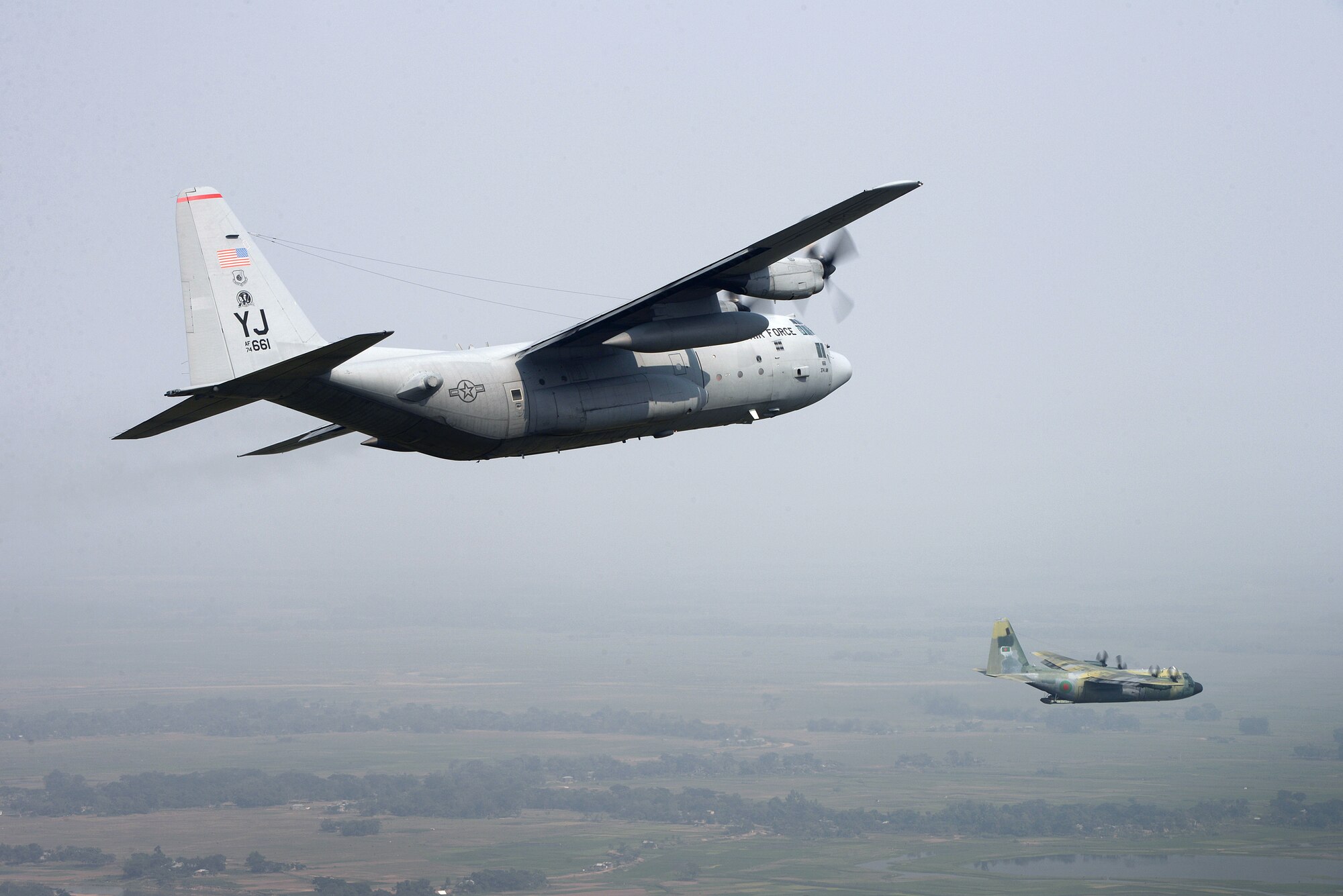 A U.S. Air Force C-130H Hercules (left) from the 374th Airlift Wing, Yokota Air Base, Japan, accompanies a Bangladesh Air Force C-130B from the 101st Special Flying Unit, BAF Base, Bangabandhu, during an airdrop mission at Exercise COPE SOUTH near Sylhet, Bangladesh, Jan. 28, 2015. COPE SOUTH is a Pacific Air Forces-sponsored, bilateral tactical airlift exercise conducted in Bangladesh, with a focus on cooperative flight operations, day and night low-level navigation, tactical airdrop, and air-land missions as well as subject-matter expert exchanges in the fields of operations, maintenance and rigging disciplines. (U.S. Air Force photo by 1st Lt. Jake Bailey/Released)