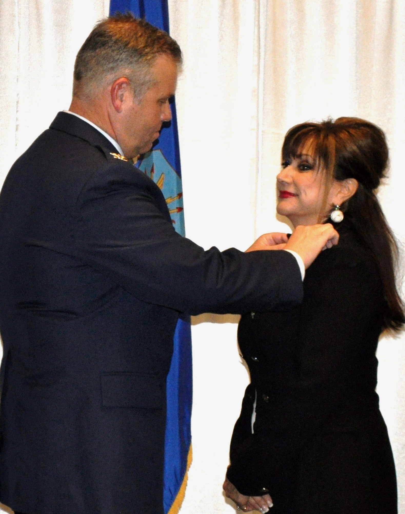 TRAVIS AIR FORCE BASE, Calif. -- Col. Patrick Williams, 349th AMW vice commander, pins a commander’s pin to the lapel of his incoming honorary commander, Kelly Placeres. Placeres is the California Department of Corrections Parole Unit Supervisor PA III for the Berkeley Unit. (U.S. Air Force photo/Ellen Hatfield)