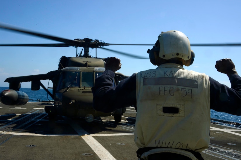 A U.S. Navy landing signal officer helps the members of the 1st Battalion, 228th Aviation Regiment land a UH-60 Blackhawk helicopter during deck landing qualifications off the coast of Honduras, Feb. 1, 2015.  The 1-228th Avn. Reg. aircrew participated in deck landing qualifications on board the USS Kauffman to qualify pilots and crew chiefs on shipboard operations.   Kauffman is on its final scheduled deployment to the U.S. Southern Command area of responsibility supporting multinational, counter-narcotics operation known as Operation Martillo. (U.S. Air Force photo/Tech. Sgt. Heather Redman)