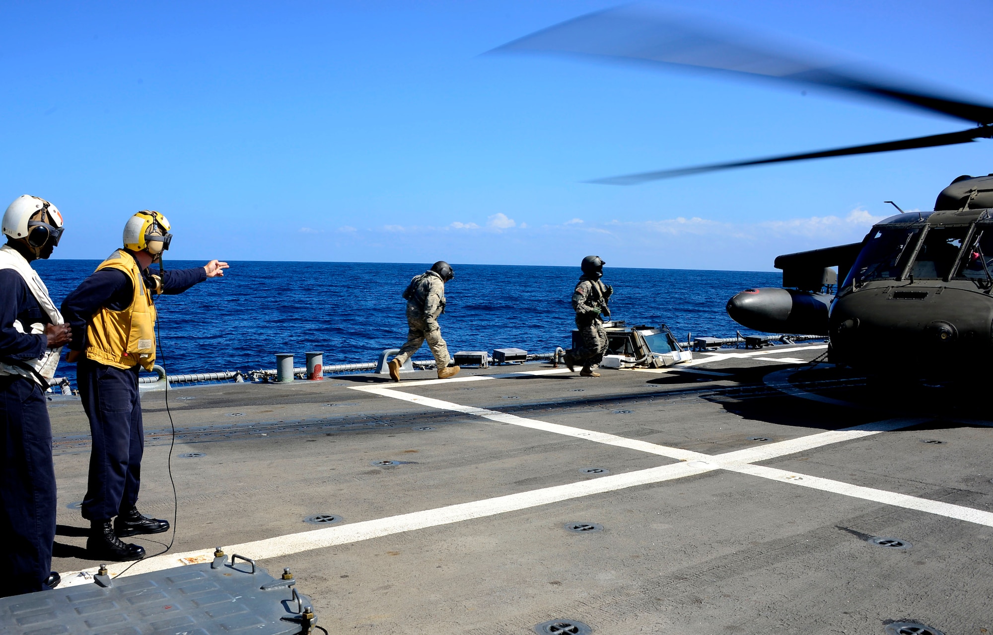 A U.S. Navy aircraft handling officer signals for members of the 1st Battalion, 228th Aviation Regiment to board a UH-60 Blackhawk helicopter during deck landing qualifications off the coast of Honduras, Feb. 1, 2015.  The 1-228th Avn. Reg. aircrew participated in deck landing qualifications on board the USS Kauffman to qualify pilots and crew chiefs on shipboard operations.  Kauffman is on its final scheduled deployment to the U.S. Southern Command area of responsibility supporting multinational, counter-narcotics operation known as Operation Martillo. (U.S. Air Force photo/Tech. Sgt. Heather Redman)