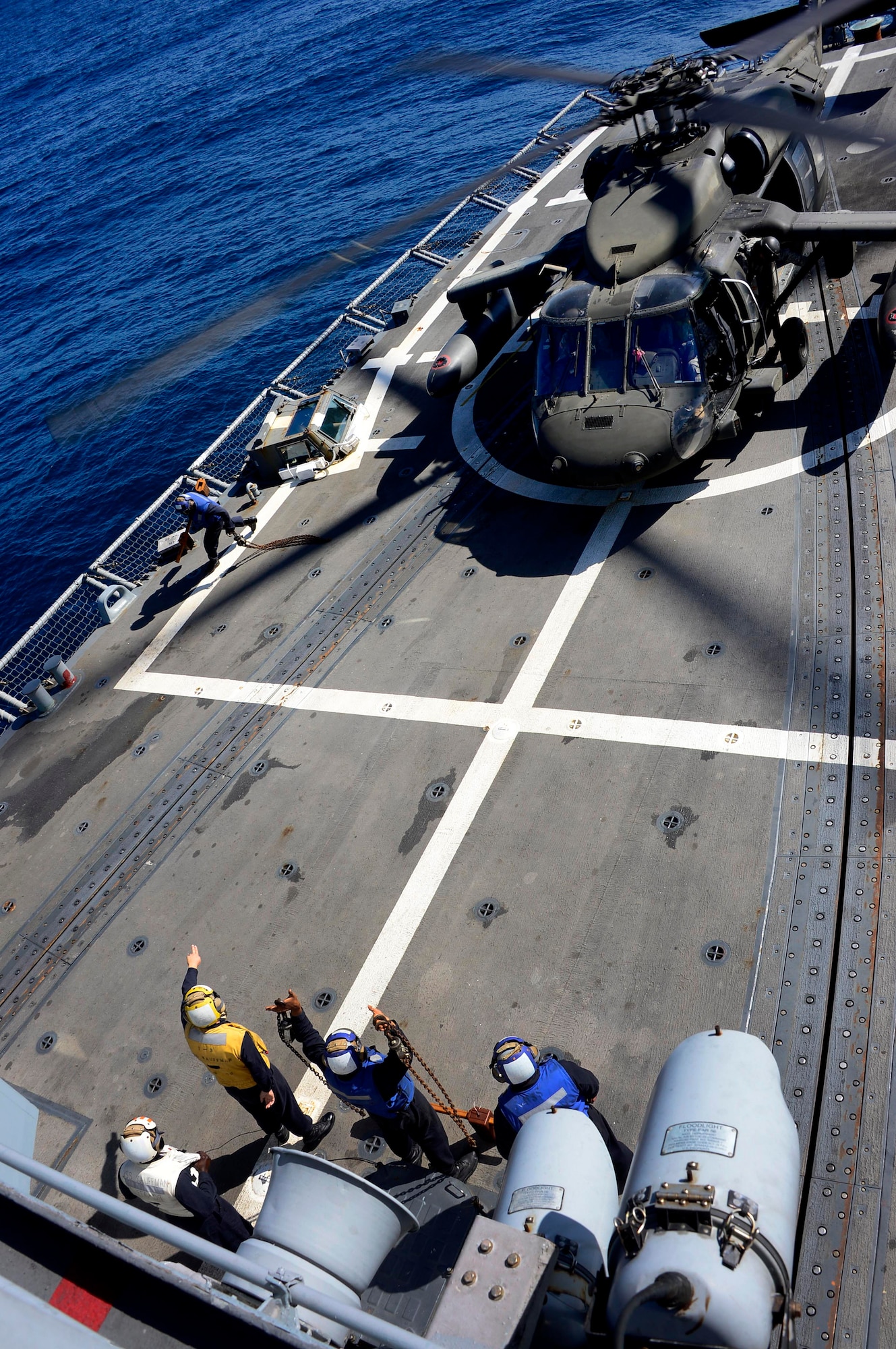 A U.S. Navy aircraft handling officer, assigned to the USS Kauffman, signals to the pilot of a UH-60 Blackhawk helicopter, assigned to the 1st Battalion, 228th Aviation Regiment, that the chalks and ties have be removed and the aircraft can take off during deck landing qualifications off the coast of Honduras, Feb. 1, 2015.  The 1-228th Avn. Reg. aircrew participated in deck landing qualifications on board the Kauffman to qualify pilots and crew chiefs on shipboard operations.  Kauffman is on its final scheduled deployment to the U.S. Southern Command area of responsibility supporting multinational, counter-narcotics operation known as Operation Martillo. (U.S. Air Force photo/Tech. Sgt. Heather Redman)