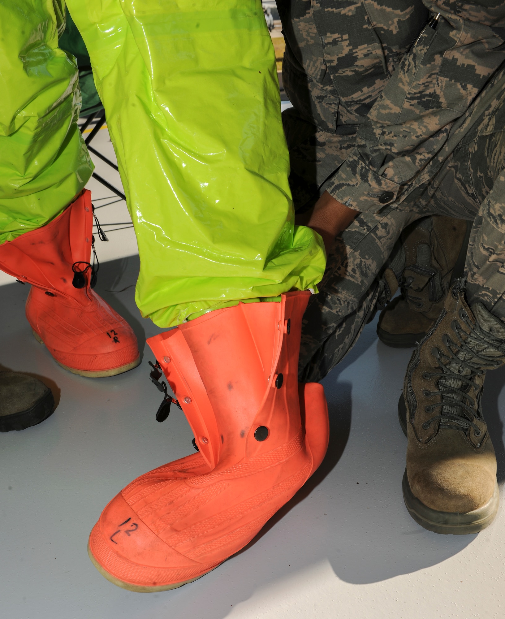 A 23d Aerospace Medicine Squadron bioenvironmental engineering technician helps a 23d civil engineer squadron firefighter don butyl rubber boots during a hazardous material incident training Jan. 28, 2015, at Moody Air Force Base, Ga. Airmen helped the technician get dressed so he could safely and quickly enter a simulated hot zone.   
(U.S. Air Force photo by Senior Airman Sandra Marrero/Released)
