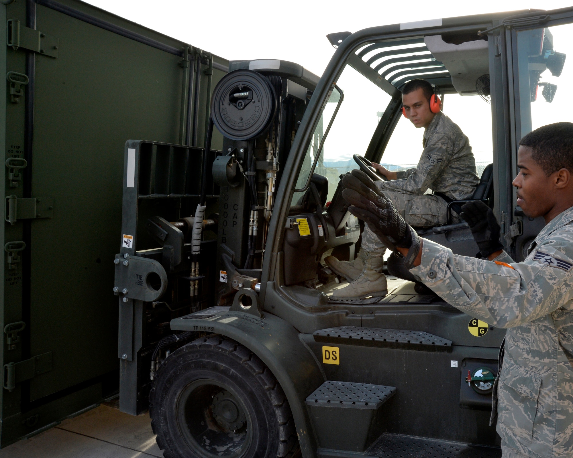 Airman 1st Class Brian Vargas, 99th Logistics Readiness Squadron Creech mobility readiness spare package Airman, left, maneuvers an internal airlift/helicopter slingable-container unit as Senior Airman Isaac Hooper, 99th LRS Creech MRSP Airman, directs him using hand signals Jan. 28, 2015 at Creech Air Force Base, Nevada. The LRS team at Creech is dedicated to providing transportation support for the fast-paced remotely piloted aircraft enterprise, maintaining an efficient supply warehouse for maintenance needs, and assisting  with transportation management and household good processing for 3,500 personnel assigned to the base. (U.S. Air Force photo by Staff Sgt. Adawn Kelsey/Released)