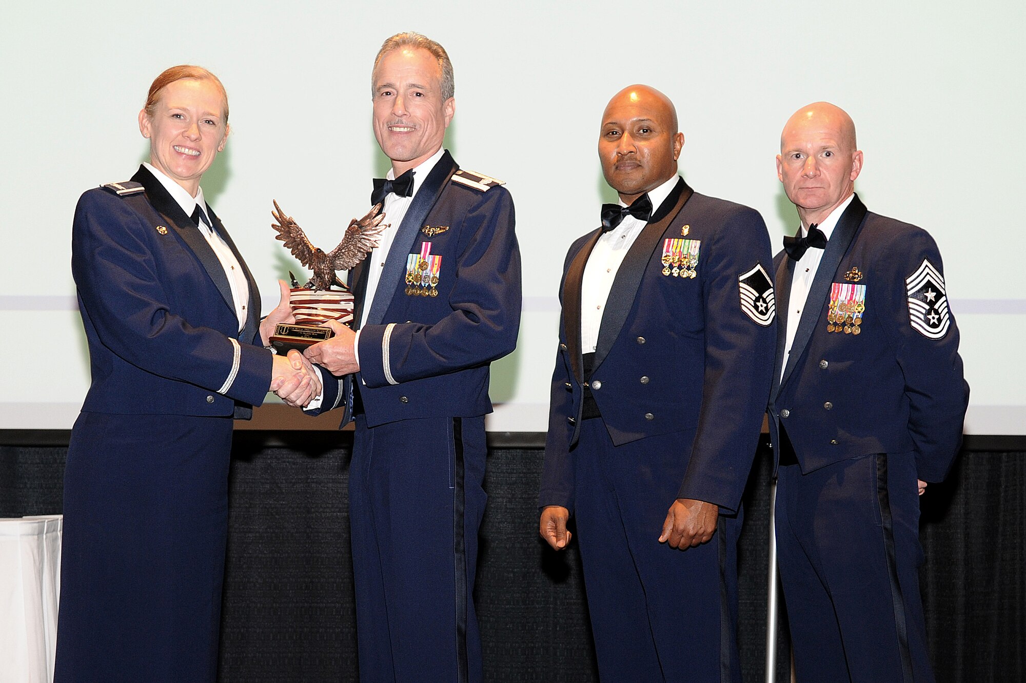 SAN ANGELO, Texas – Col. Kimberlee P. Joos, 17th Training Wing Commander, and Chief Master Sgt. Thomas F. Good, 17th TRW Command Chief, present Lt. Col. Paul T. Miller Jr., 17th Medical Operations Squadron Commander, and Master Sgt. Marvin L. Hawkins Jr., 17th MDOS superintendent, the 17th Training Wing 2014 Unit of the Year award during the Annual Awards Banquet at the McNease Convention Center Jan. 30. (U.S. Air Force photo/ Airman 1st Class Devin Boyer)