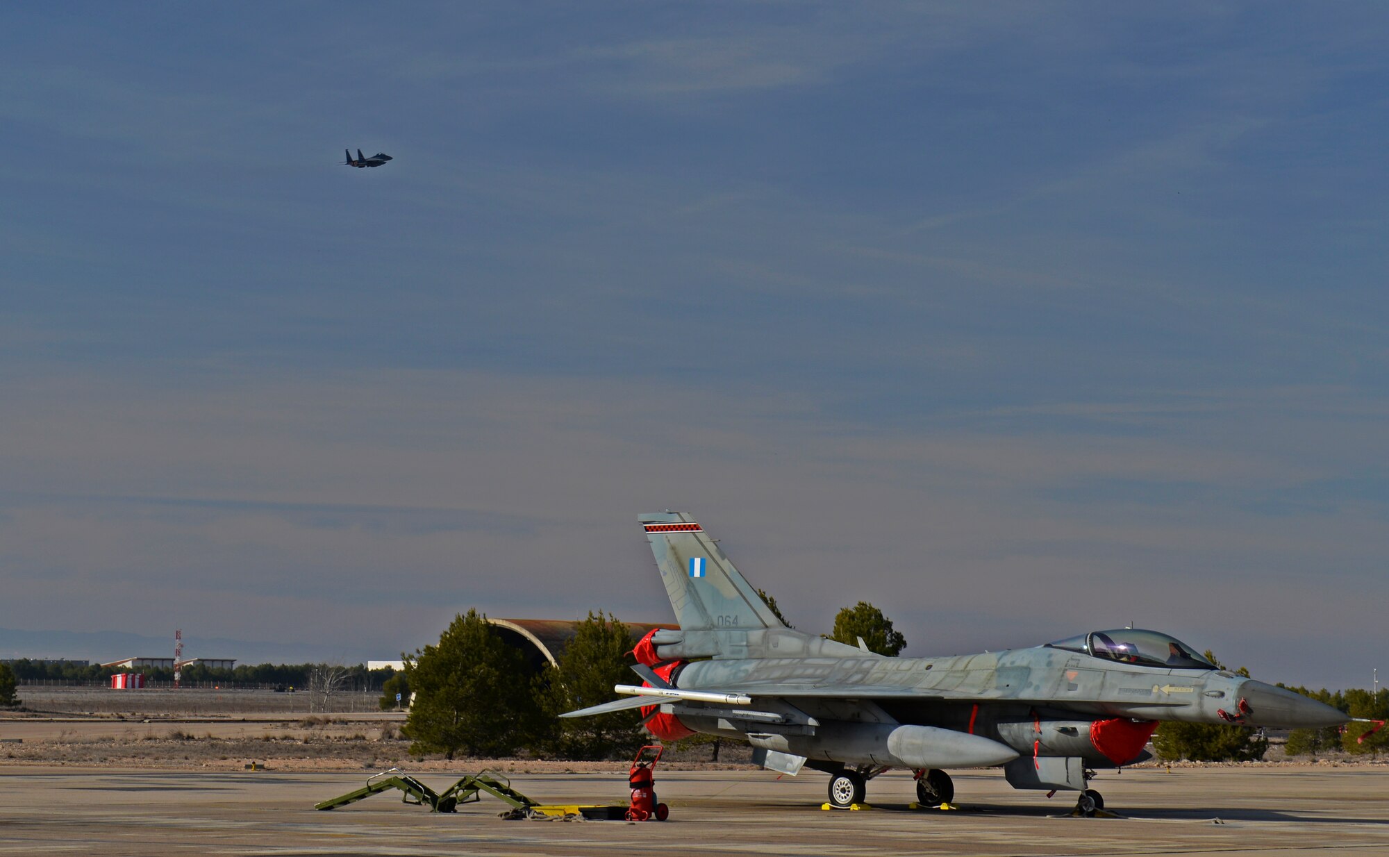 A 492nd Fighter Squadron F-15E Strike Eagle flies over a Greek F-16C Fighting Falcon on its way back to Royal Air Force Lakenheath, upon departing Los Llanos Air Base, Spain, Jan. 29, 2015. The 492nd FS left Spain upon the cancelation of Tactical Leadership Programme 2015-1, a NATO exercise that develops leadership and interoperability amongst allies.  The training event was cut short after 11 airmen from the Greek and French air forces lost their lives following an aircraft crash.  (U.S. Air Force photo by Airman 1st Class Erin R. Babis/Released)
