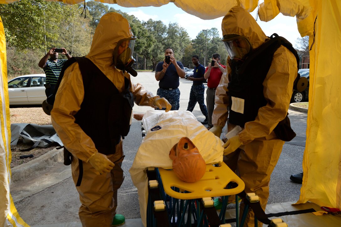 Two Navy personnel prepare to remove contaminated clothing from a mannequin as other attendees watch during a training exercise at Marine Corps Logistics Base Albany, recently.  
