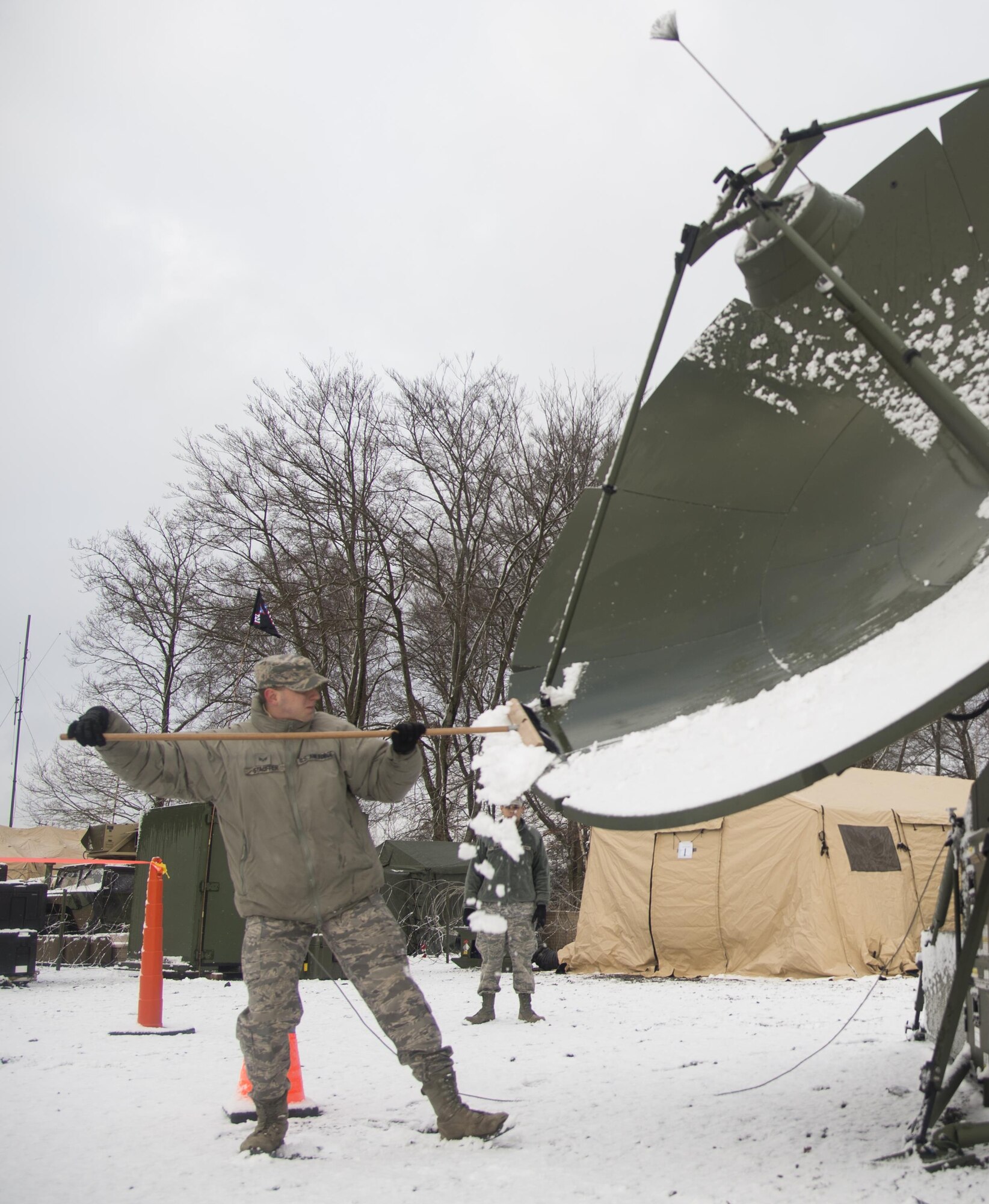 Senior Airman Erik Stauffer cleans snow off of a satellite during exercise Juniper Thunder Jan. 30, 2015, at Ramstein Air Base, Germany. Juniper Thunder aimed to help the interoperability between Air Force and Army combat communications systems. Stauffer is a transmissions systems technician assigned to the 1st Combat Communications Squadron. (U.S. Air Force photo/Senior Airman Jonathan Stefanko)