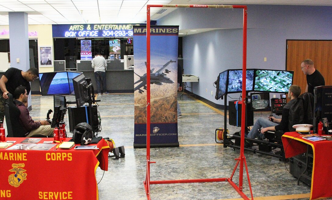 Two students from West Virginia University fly simulators during a recruiting display at West Virginia University Jan. 23, 2015. The 4th Marine Corps District Flight Operation Program, also known as MCFOP, and the Enhanced Marketing Vehicle team, Sgt. Christian Todd (left)and Sgt. Travis Brockman (right) assist Recruiting Station Frederick’s Officer Selection Office during an aviation enhanced area canvassing event geared toward aviation recruiting. The new simulators allow Marines to interact with students in a more hands-on environment.   (U.S. Marine Corps photo by Cpl. Amber Williams/Released)