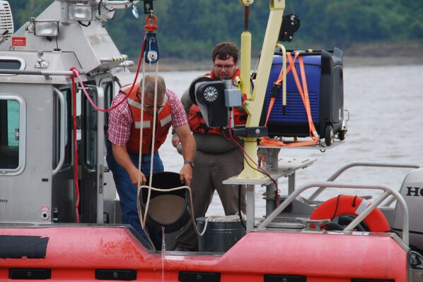 Thad Pratt, ERDC, and Richie McComas of the Corps' Vicksburg District, pour off excess water from a river sediment sample prior to bagging and logging. 