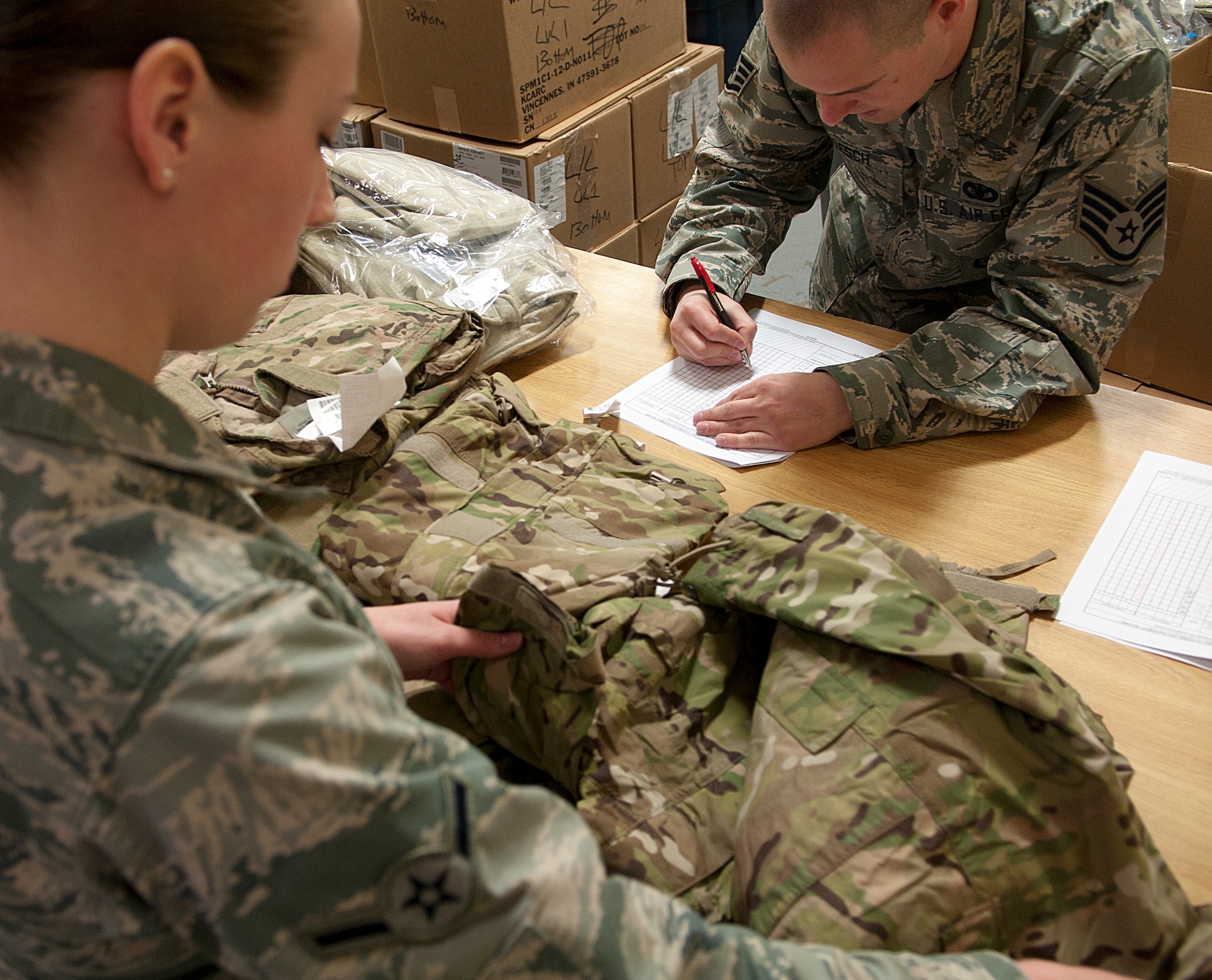 Airman Chelsea Kidman, 790th Missile Security Forces Squadron Security Support Team, inspects her new uniforms as Staff Sgt. Richard Roesch, 90th Security Support Squadron assistant NCO-in-charge of supply, checks the gear off a list Feb. 2, 2015, in the Peacekeeper High Bay on F.E. Warren Air Force Base, Wyo. The new uniform’s design helps defenders blend in to the operating environment of F.E. Warren and the missile complex. (U.S. Air Force photo by Airman 1st Class Brandon Valle) 