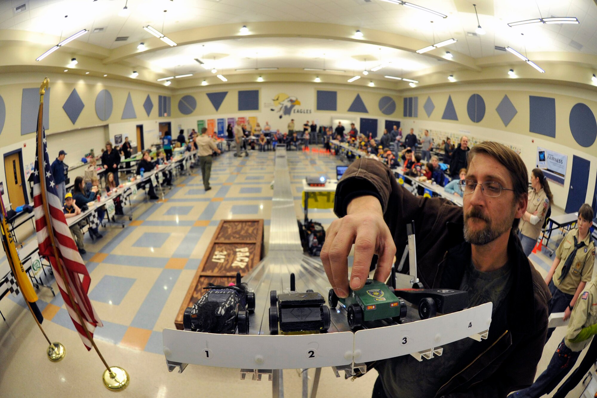 Scott Smith, retired Air Force member from the 92nd Maintenance Group and a parent volunteer, places the Pinewood Derby cars at the beginning of the track before a race Jan. 31, 2015, at Fairchild Air Force Base, Wash. Smith was in charge of the races, which included launching the cars down the track and tracking the race times with his computer. (U.S. Air Force photo/Airman 1st Class Nicolo J. Daniello) 