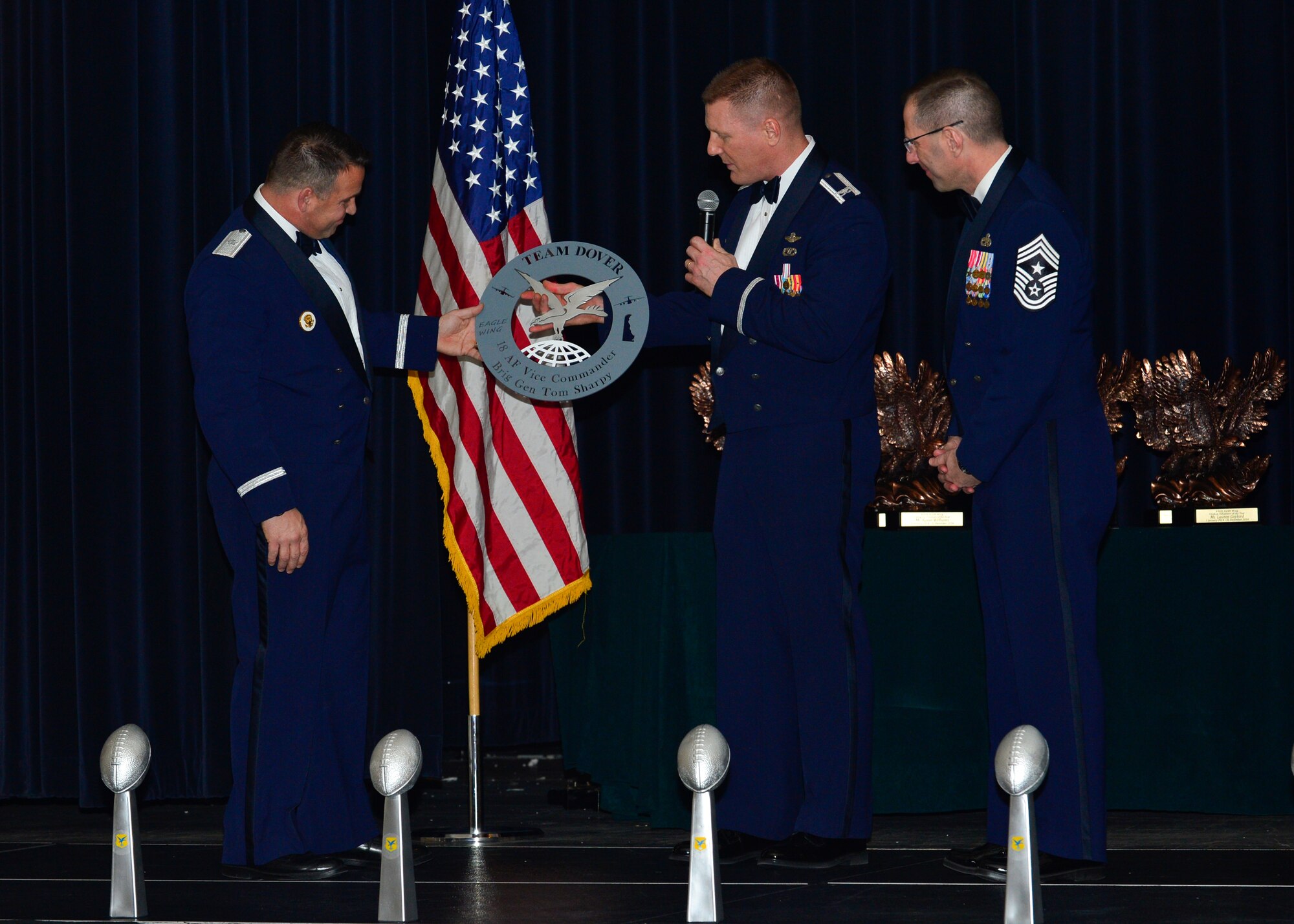 Col. Michael Grismer, 436th Airlift Wing commander, and Chief Master Sgt. Stanley Cadell, 436th AW command chief, present Brig. Gen. Thomas Sharpy, 18th Air Force vice commander, with the Eagle Medallion during the 2014 Annual Awards Ceremony Jan 30, 2015, at the Rollins Center inside of Dover Downs, Dover, Del. Sharpy was the invited to be the guest speaker during the ceremony. (U.S. Air Force photo/Airman 1st Class William Johnson)