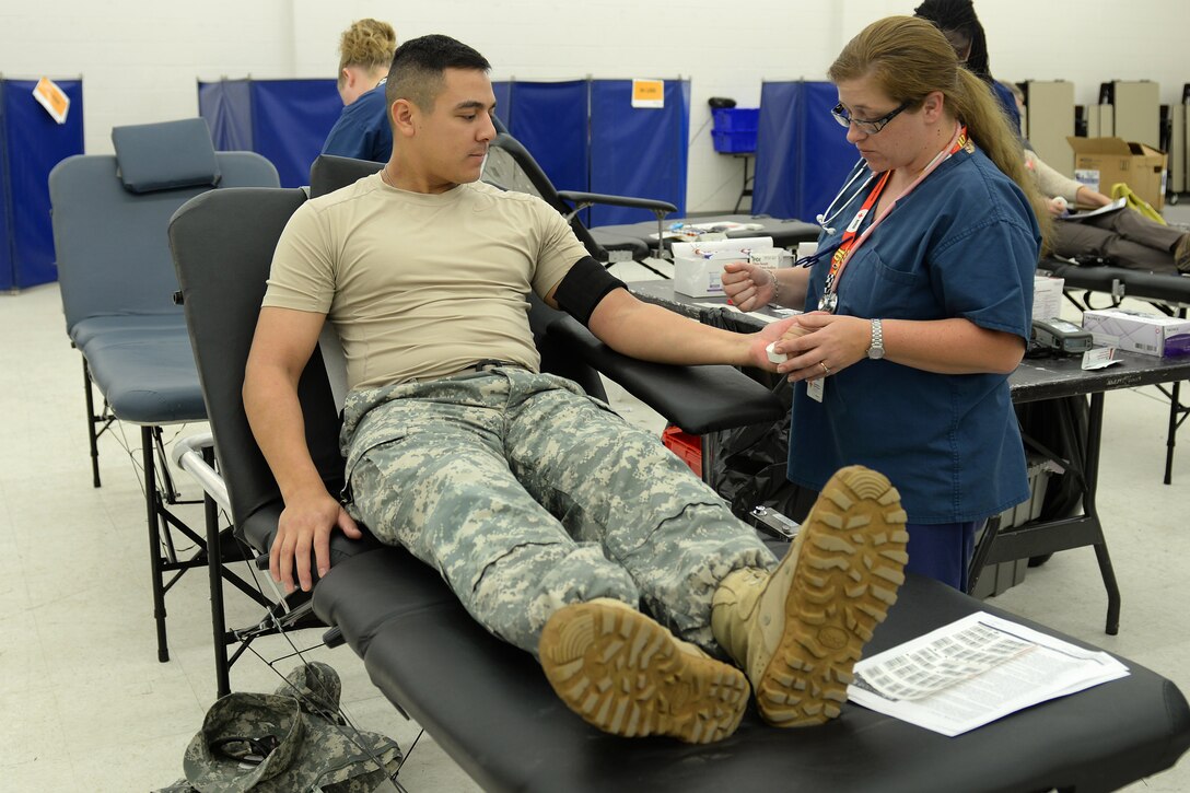 Krissy Calvert, American Red Cross technician, questions U. S. Army Staff Sgt. Jason Panergo, 128th Aviation Brigade weapons instructor, before drawing blood at a blood drive held at Fort Eustis, Va., Oct. 15, 2014. McDonald Army Health Center hosts blood drives quarterly to earn credit for units of blood with the American Red Cross, saving both money and lives. (U.S. Air Force photo by Staff Sgt. Teresa J. Cleveland/Released)