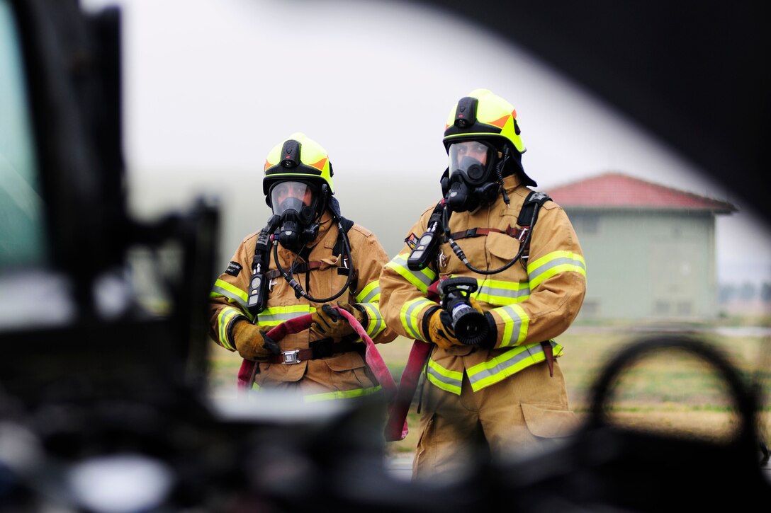 Firefighters from 39th Civil Engineer Squadron fire emergency services simulate extinguishing a fire during a base-wide exercise Jan. 28, 2015, at Incirlik Air Base, Turkey. The exercise involved a vehicle catching on fire and tested the firefighter’s response time and efficiency at putting out the blaze. (U.S. Air Force photo by Senior Airman Krystal Ardrey/Released)