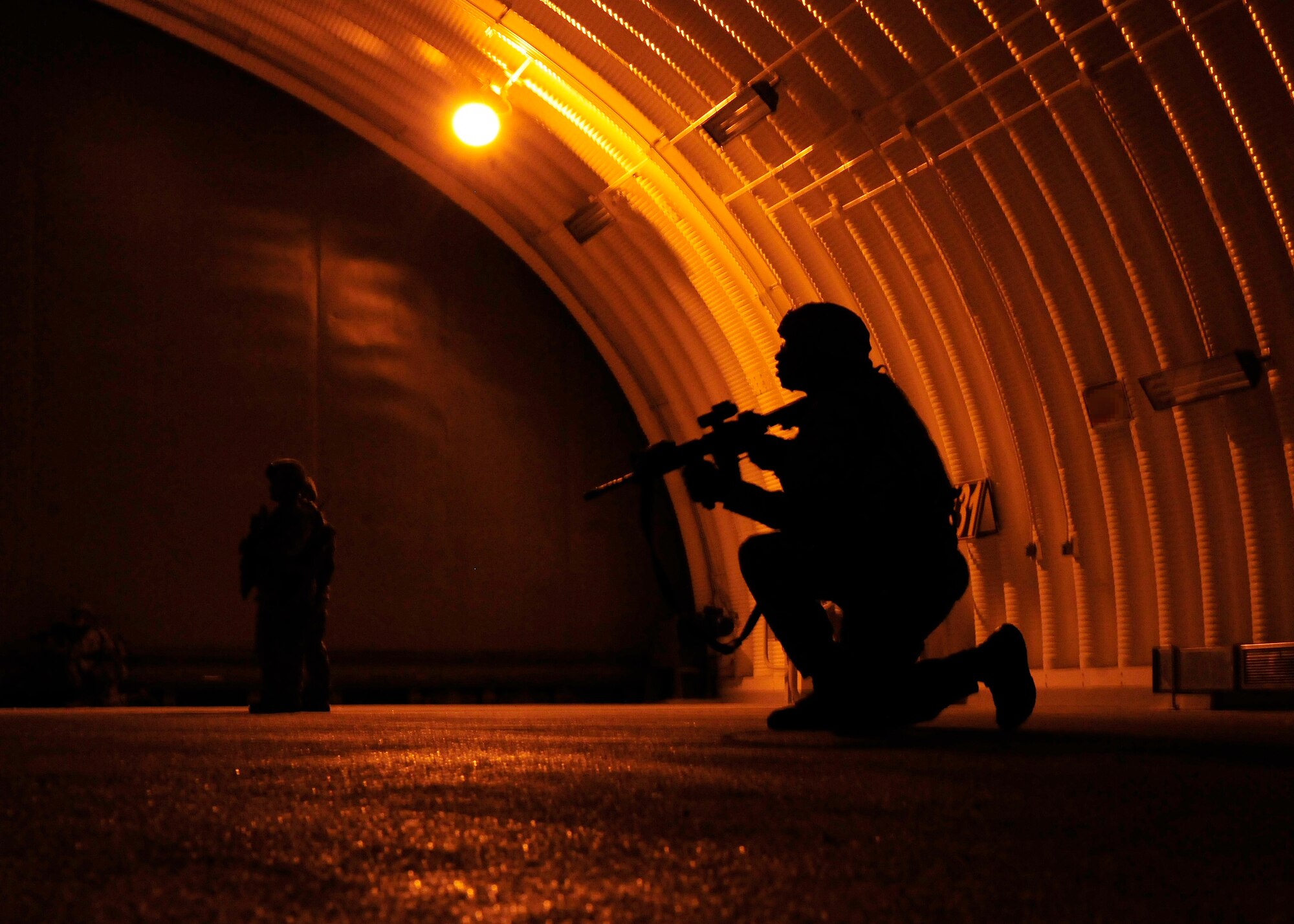 A 39th Security Forces Squadron Airman crouches inside of an aircraft shelter during a base-wide exercise Jan. 28, 2015, at Incirlik Air Base, Turkey. The 39th SFS defenders responded to an active shooter incident inside of the shelter as part of the exercise. (U.S. Air Force photo by Senior Airman Krystal Ardrey/Released)